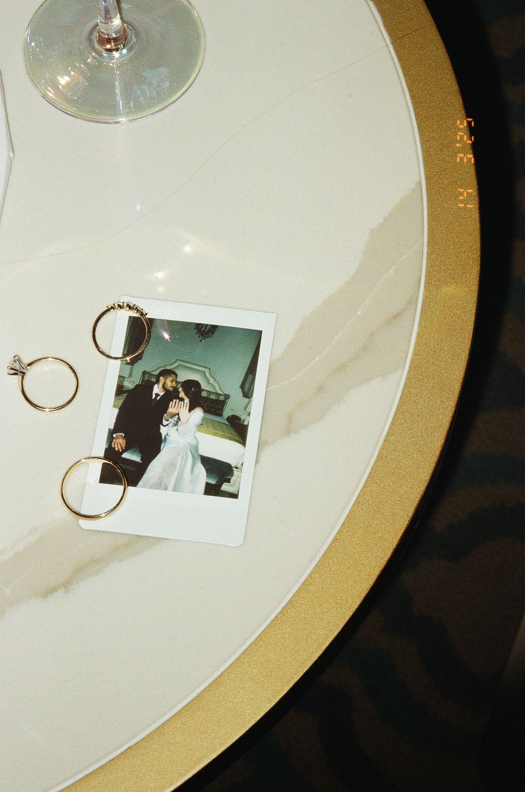 White plates with gold rims display small Polaroid photos and delicate gold hoop earrings in an artistic arrangement.