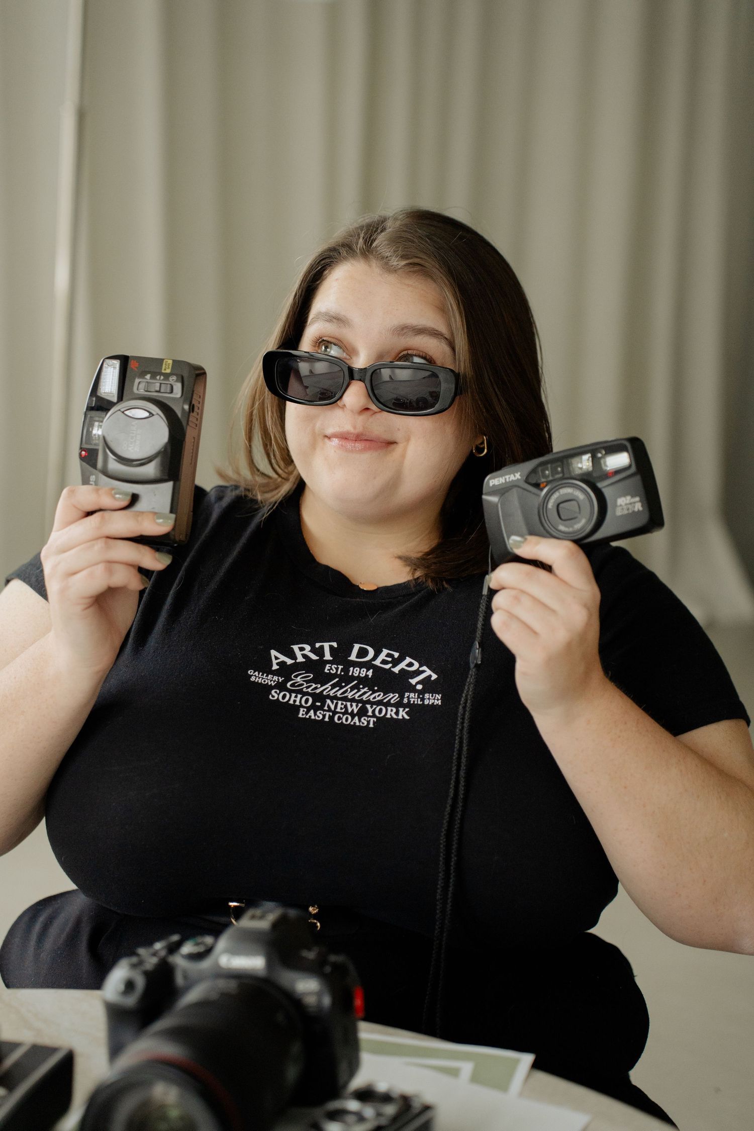 Person in black Art Dept shirt shows off multiple cameras while making playful expressions in a photo series.