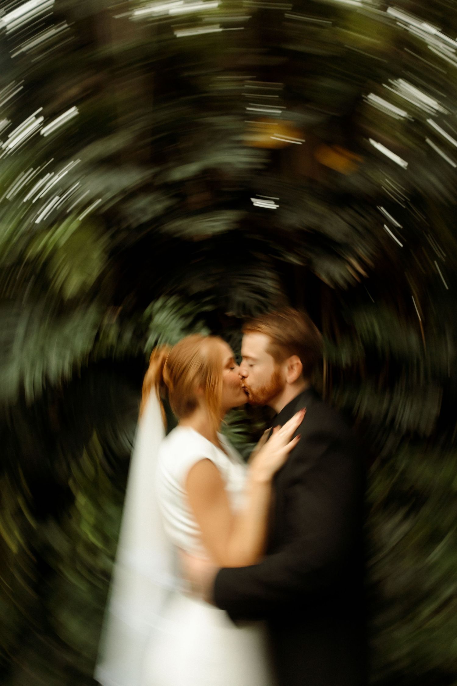 Artistic swirling motion effect captures a romantic wedding moment in a garden setting.