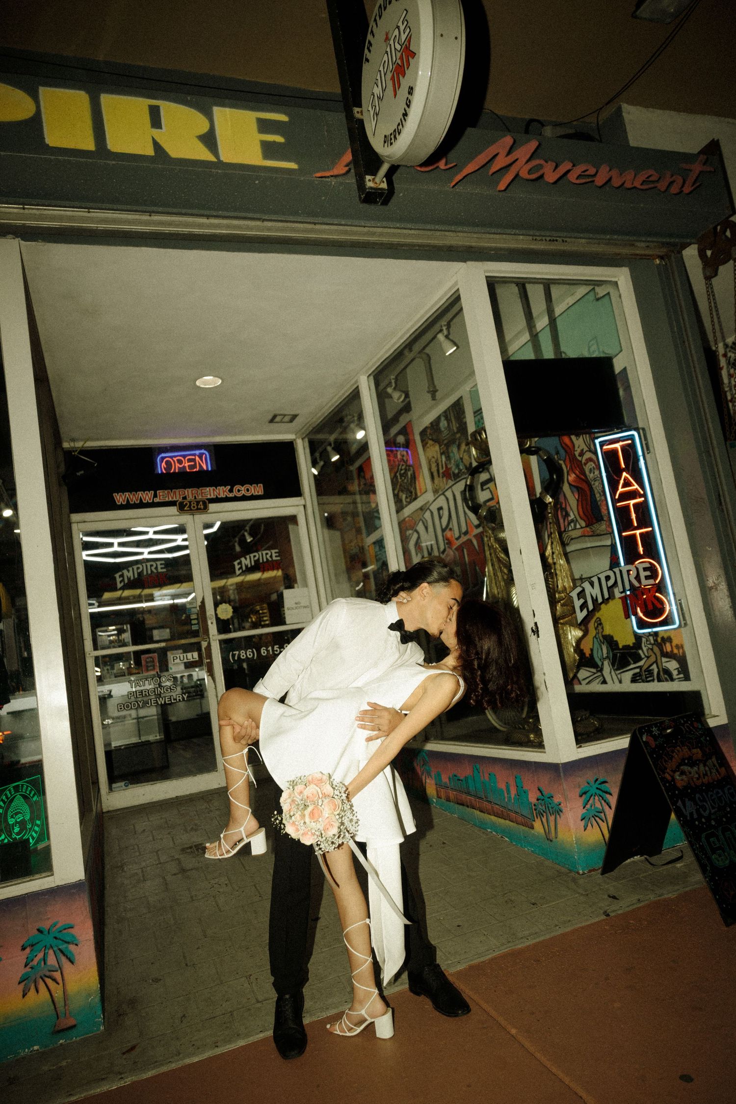Three sequential candid photos showing a couple in formal attire leaning over in front of a storefront at night.