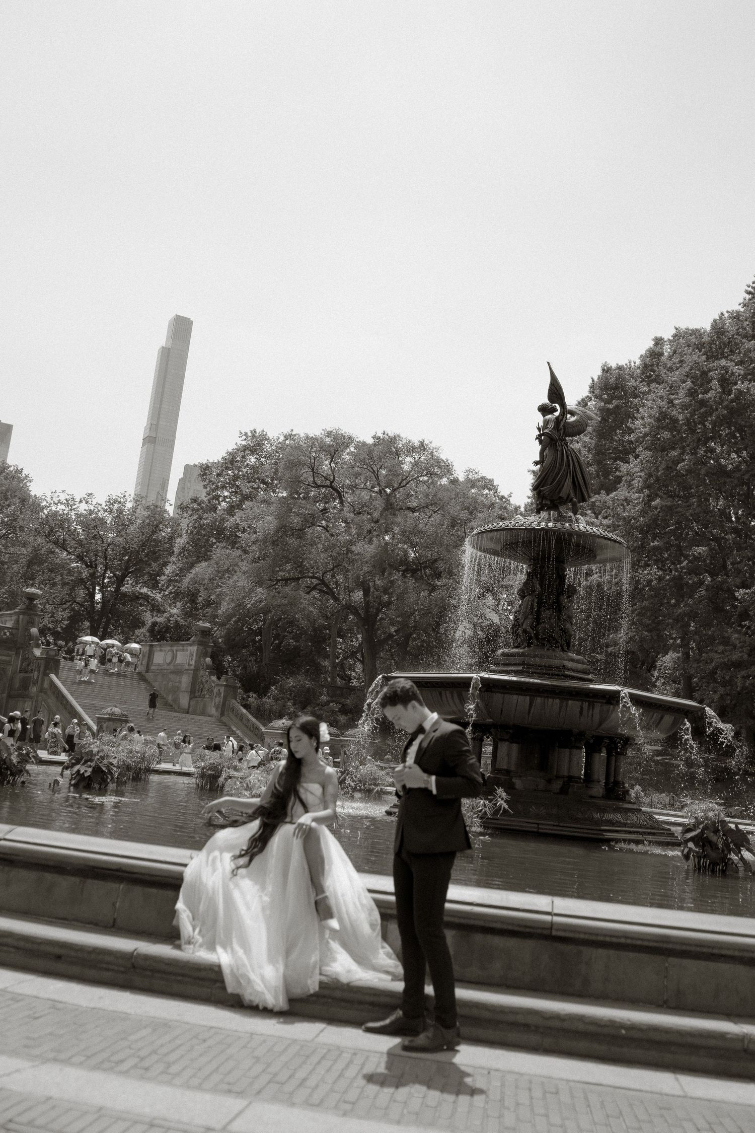 A romantic black and white scene at Bethesda Fountain in Central Park with dancing couple and iconic tower in background.