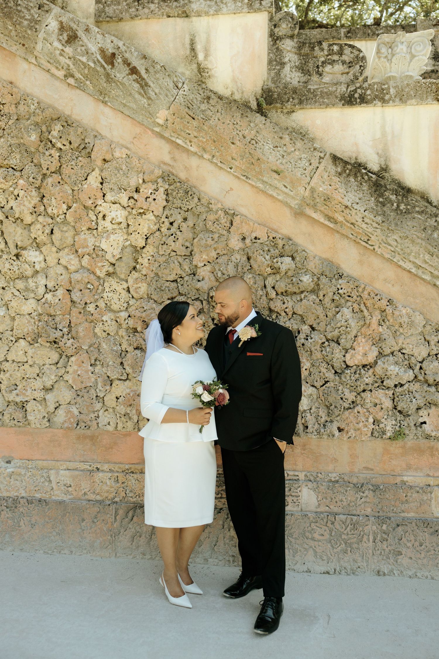 A couple shares intimate dance poses against a rustic stone wall backdrop.