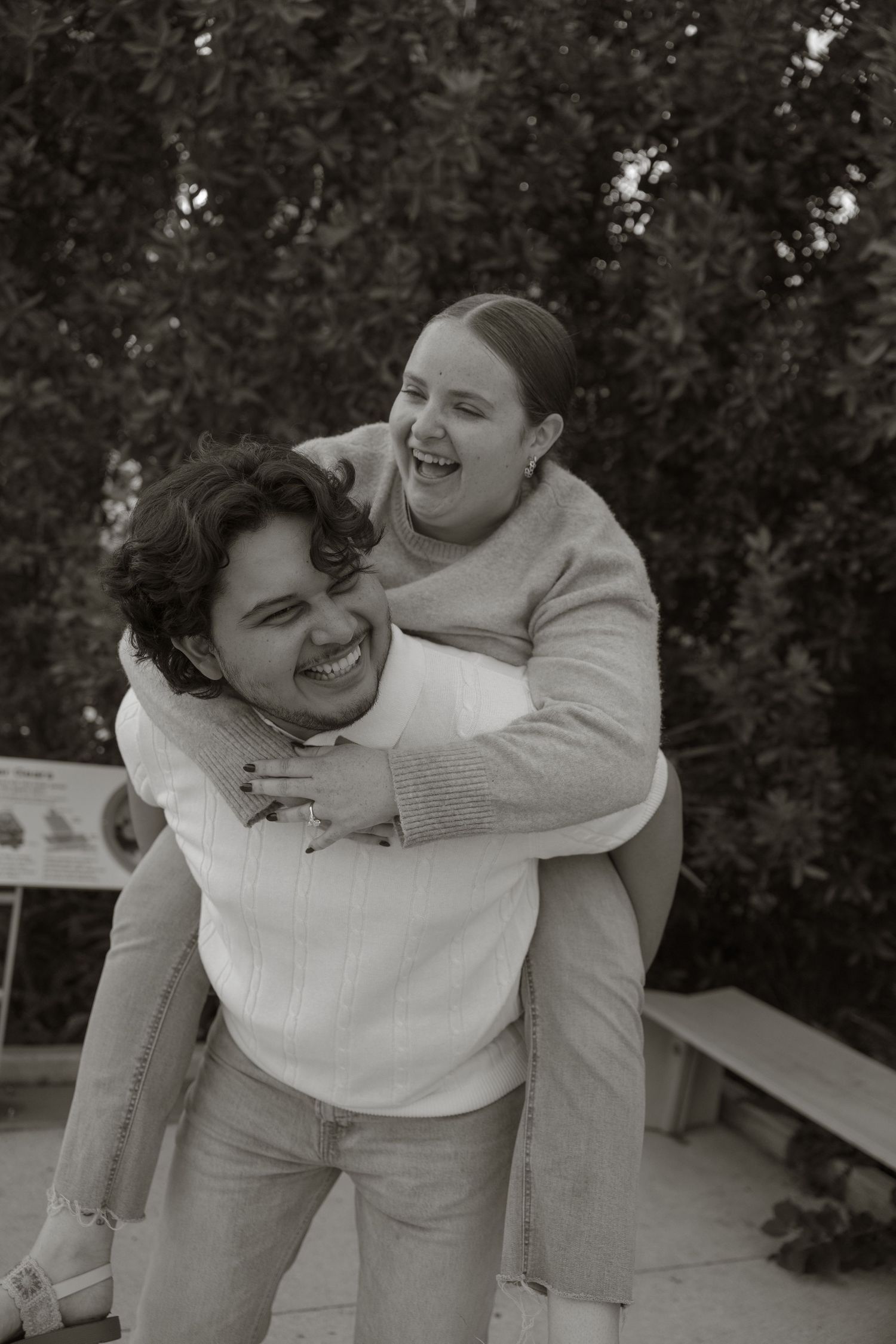 A playful sequence of black and white photos showing two people embracing and laughing together outdoors.