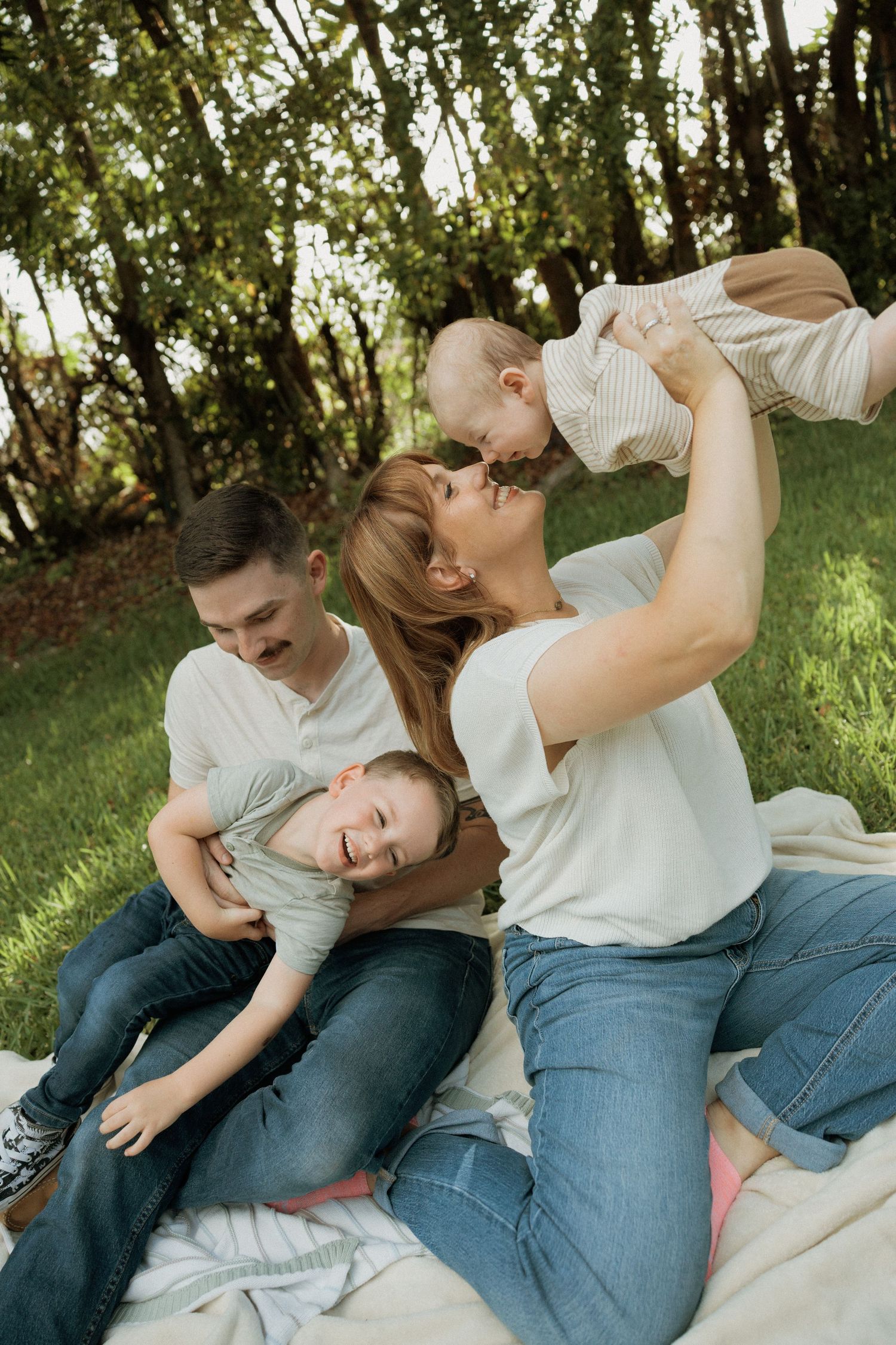 A playful sequence of four candid moments captured outdoors on a blanket in a sunlit garden setting.