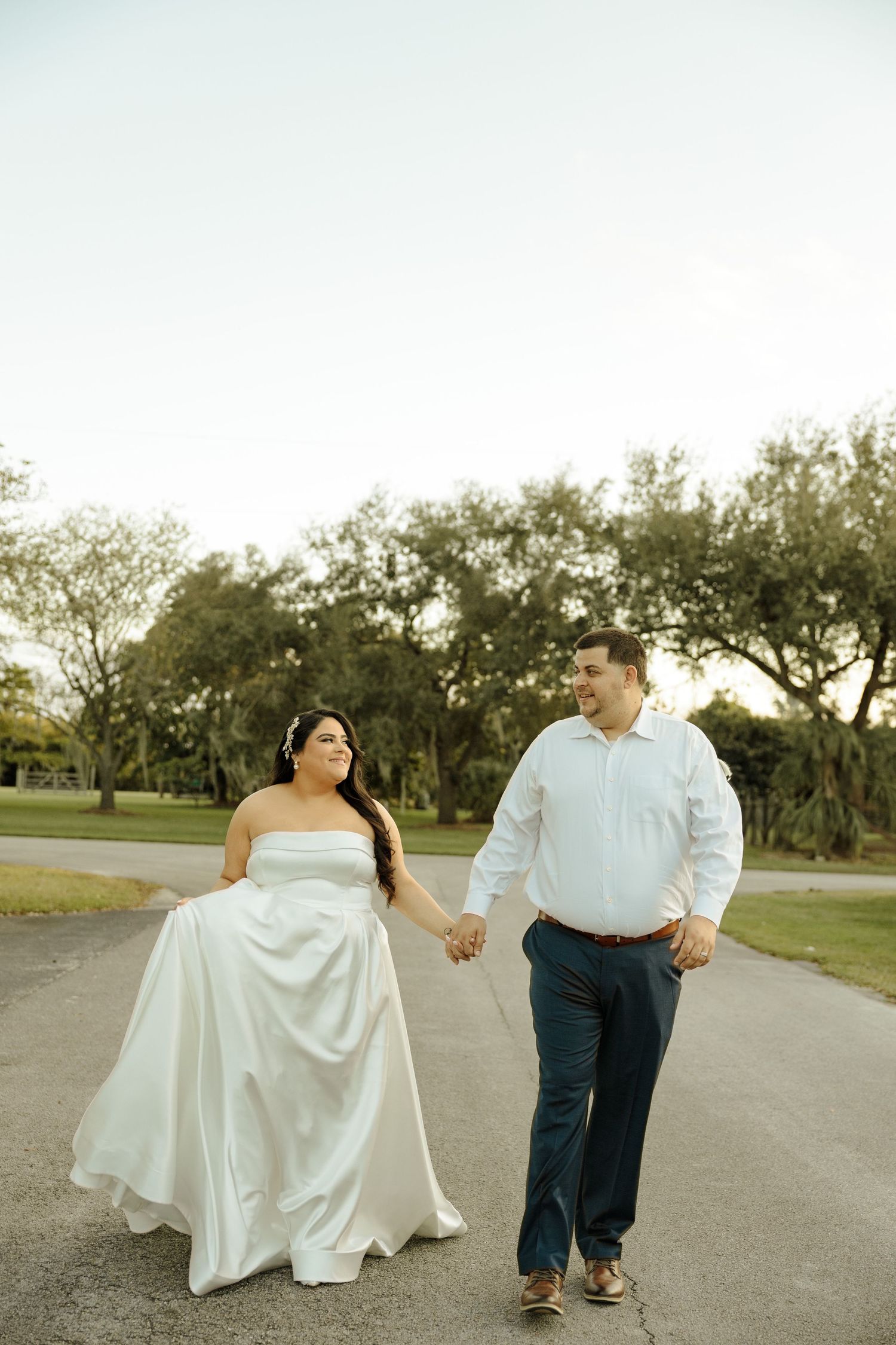 Couple walking together on a path wearing wedding attire.