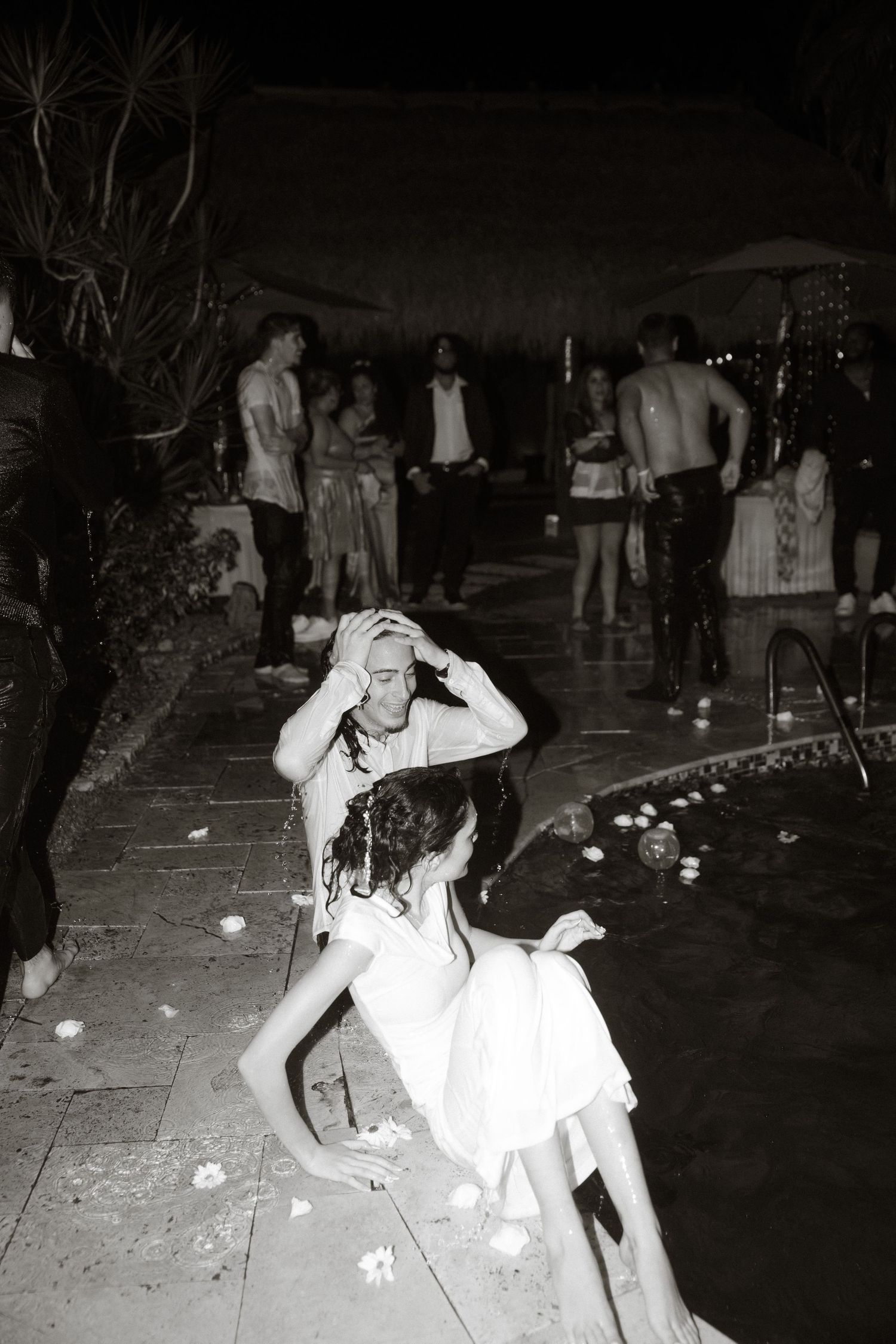 People dancing and celebrating at a nighttime pool party.