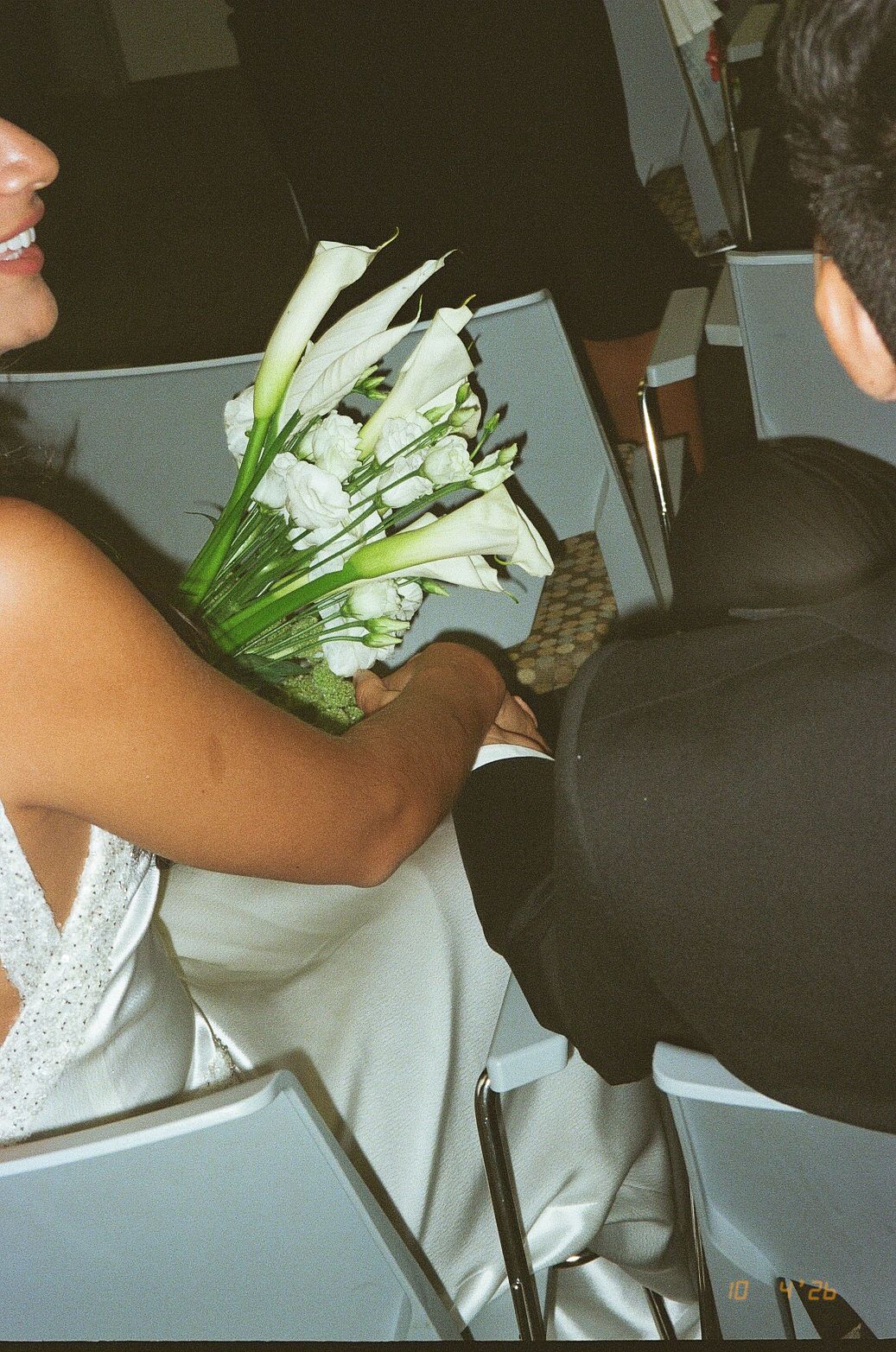 Bride holding white calla lily bouquet beside groom in black suit at wedding ceremony.
