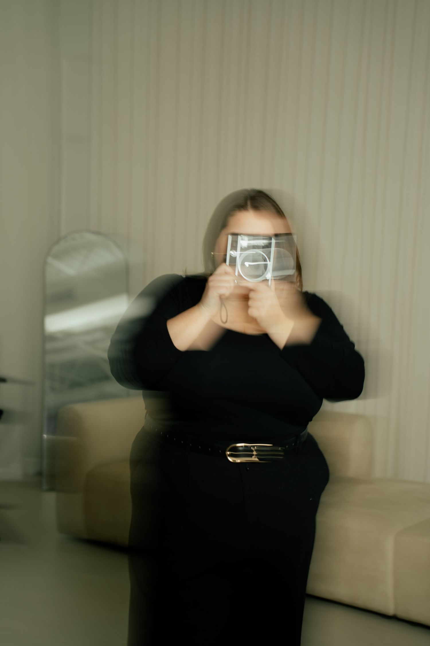 A sequence of photos showing someone in black clothing taking a selfie with a digital camera against a light background.