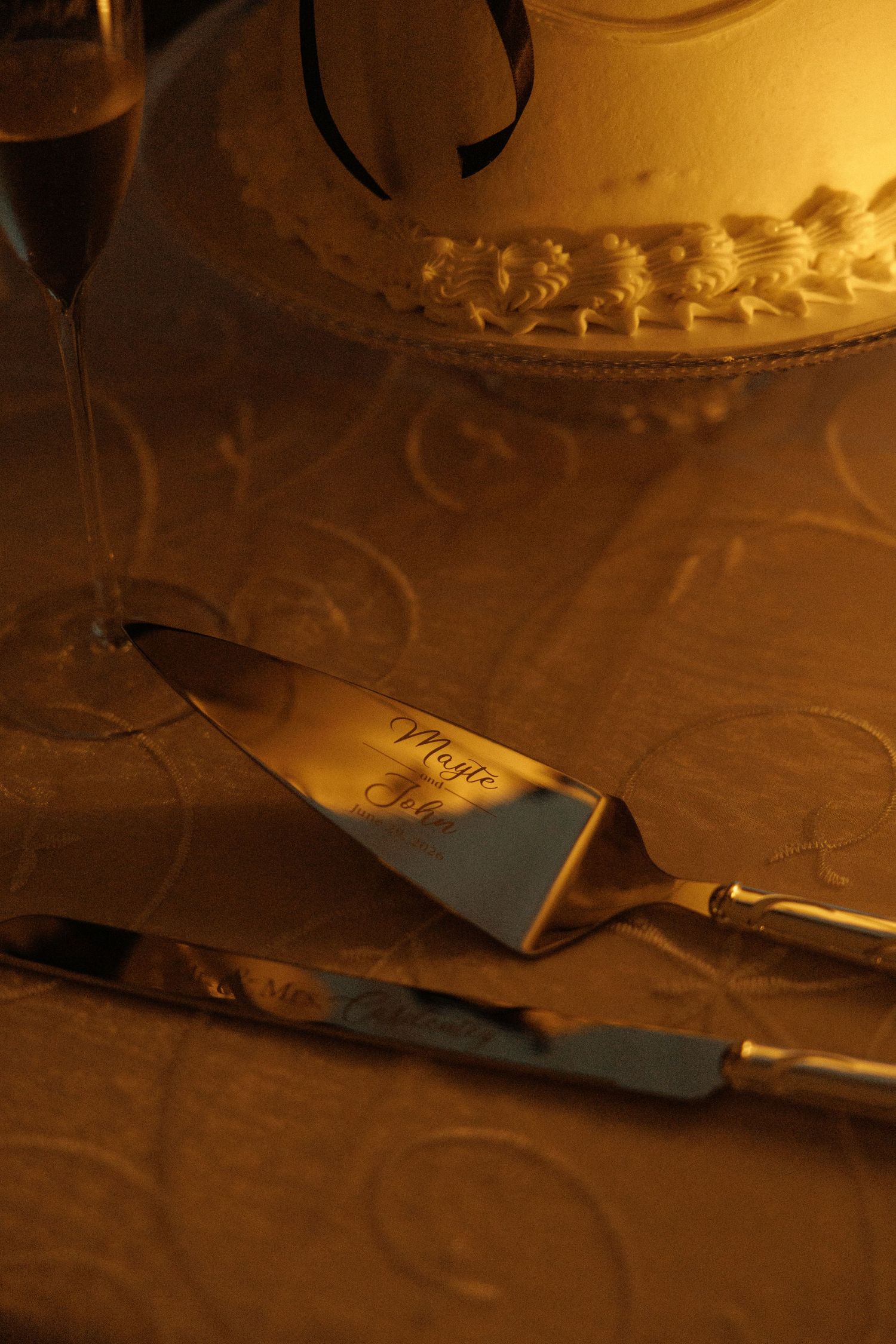 Elegant wedding cake with engraved silver cake server and knife set on a golden damask tablecloth.