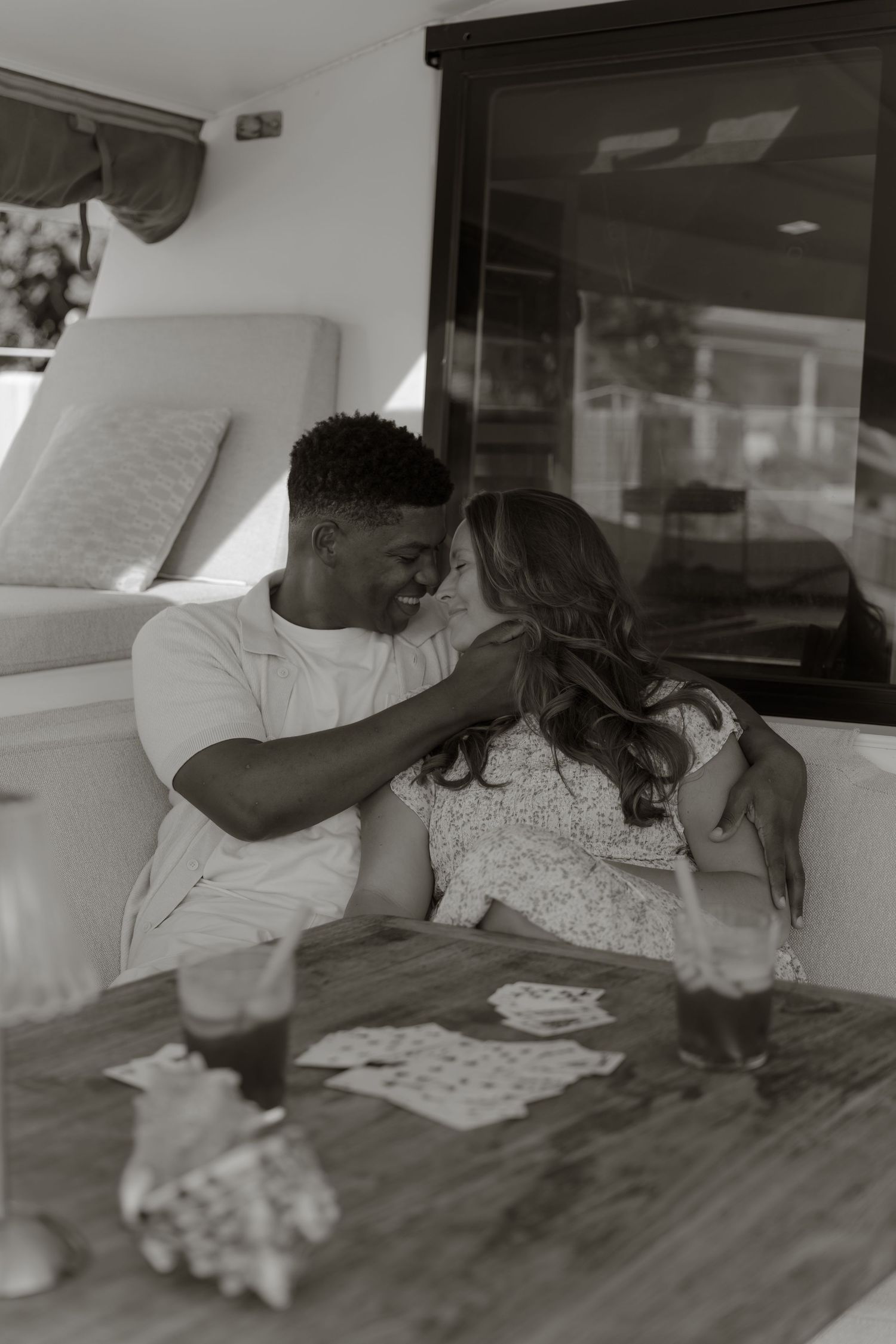 Black and white photo of a loving couple sharing a romantic moment at a table inside a boat cabin.