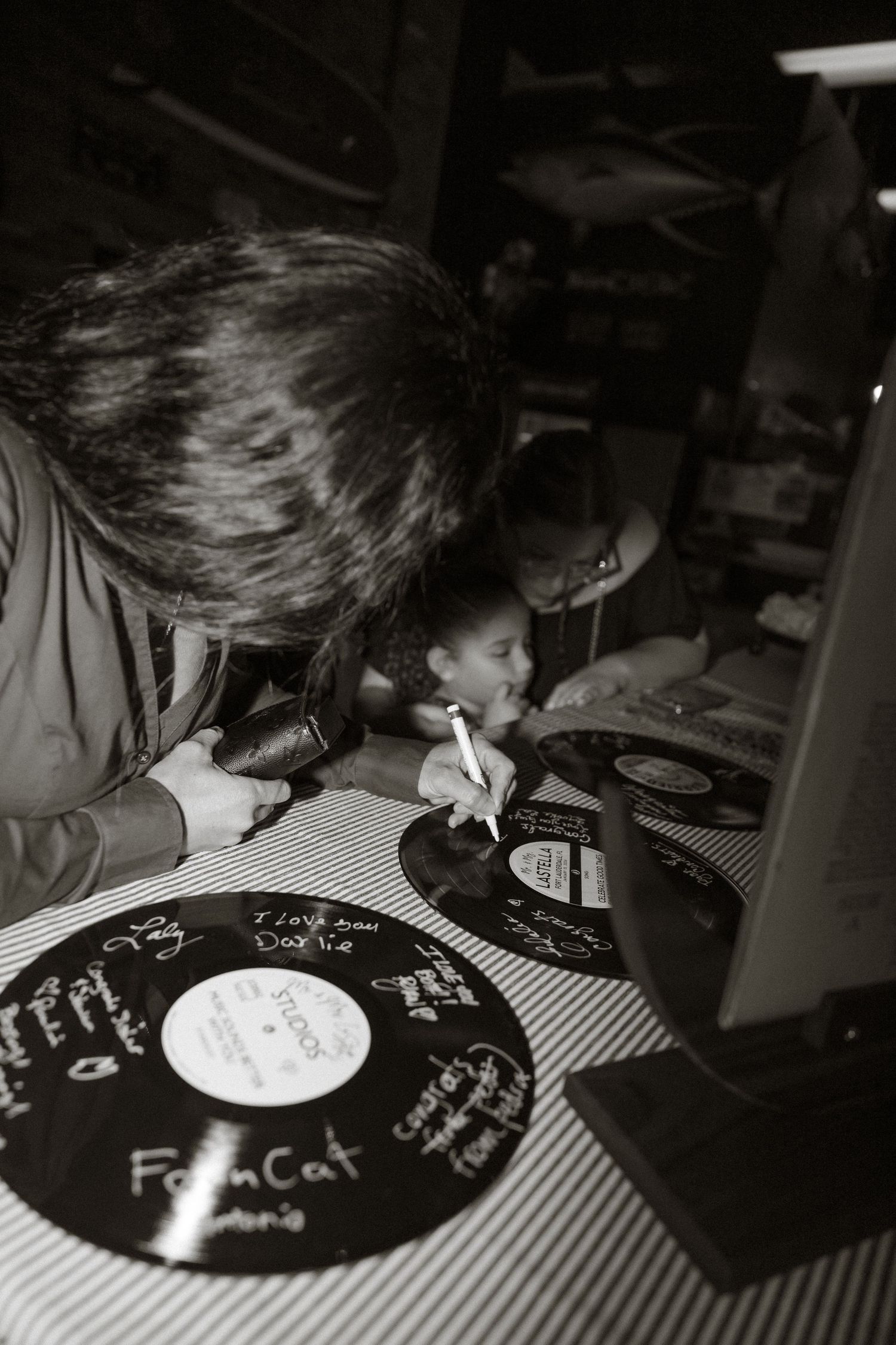 Black and white photo series showing someone examining vinyl records on a striped tablecloth.