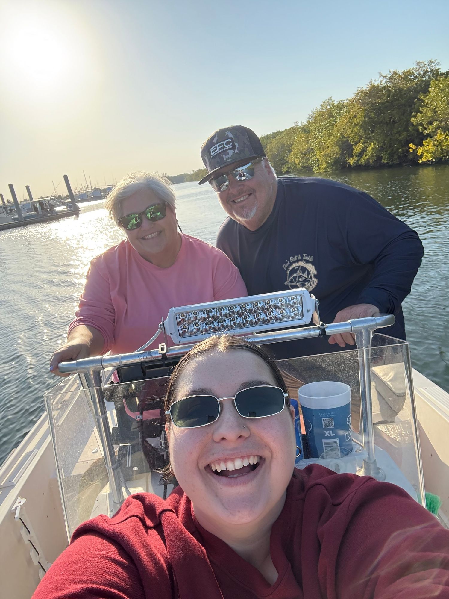 Group enjoying a sunny day on a boat with sunglasses and drinks on calm waters.