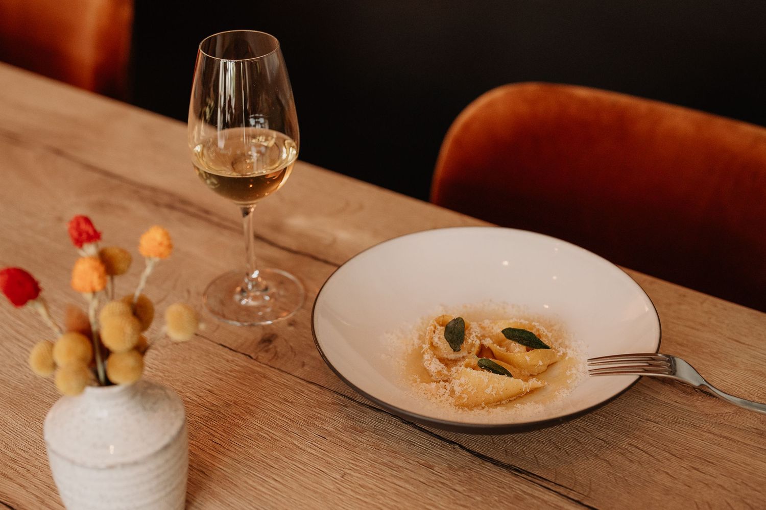 Artfully presented small bites and appetizers on white plates arranged on a dark wooden dining table.