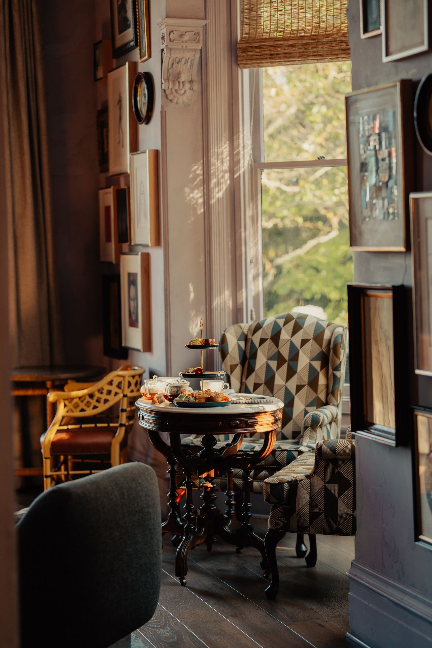 Warm sunlit restaurant interior with wooden tables and chairs casting long shadows through large windows.