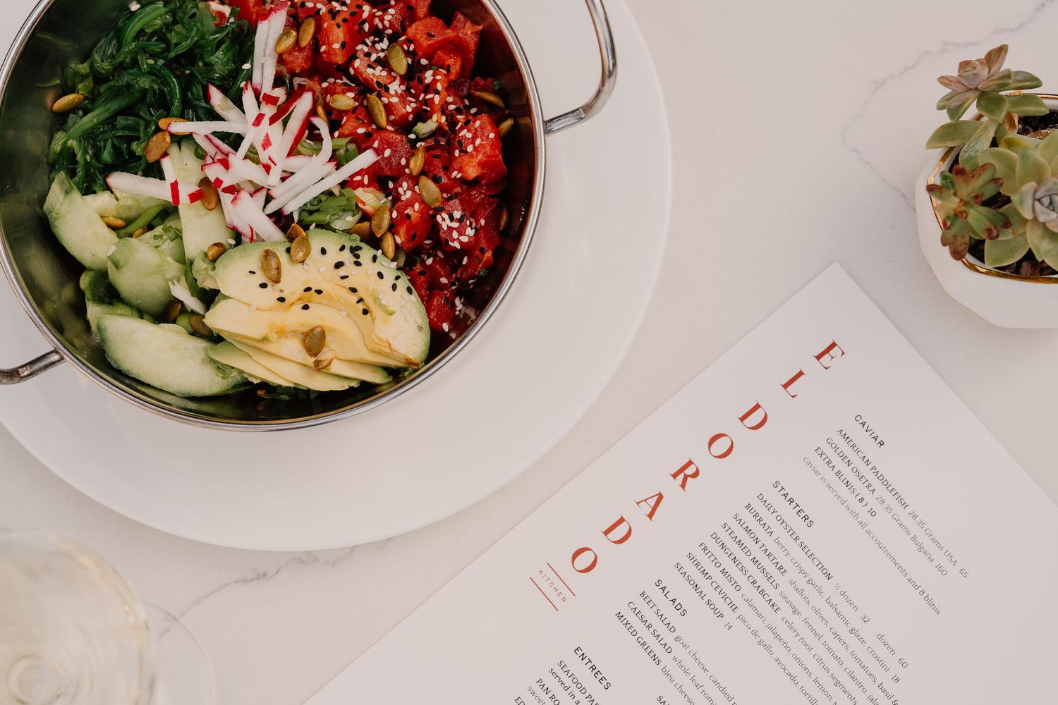 A collection of modern restaurant dishes and menu pages arranged on a white surface in a stylish presentation.