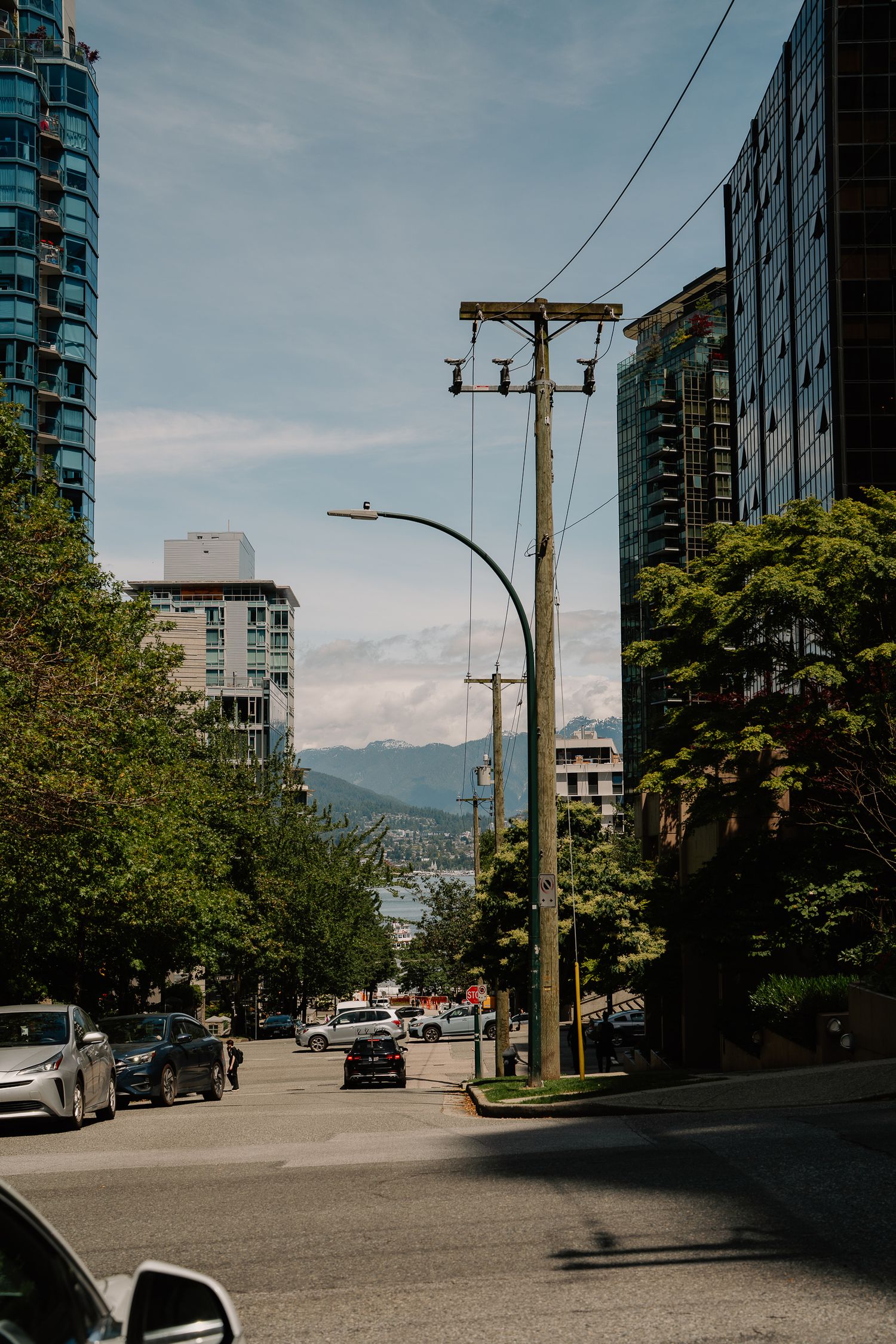 Urban street view with tall residential buildings, utility poles, and mountains visible in the background.