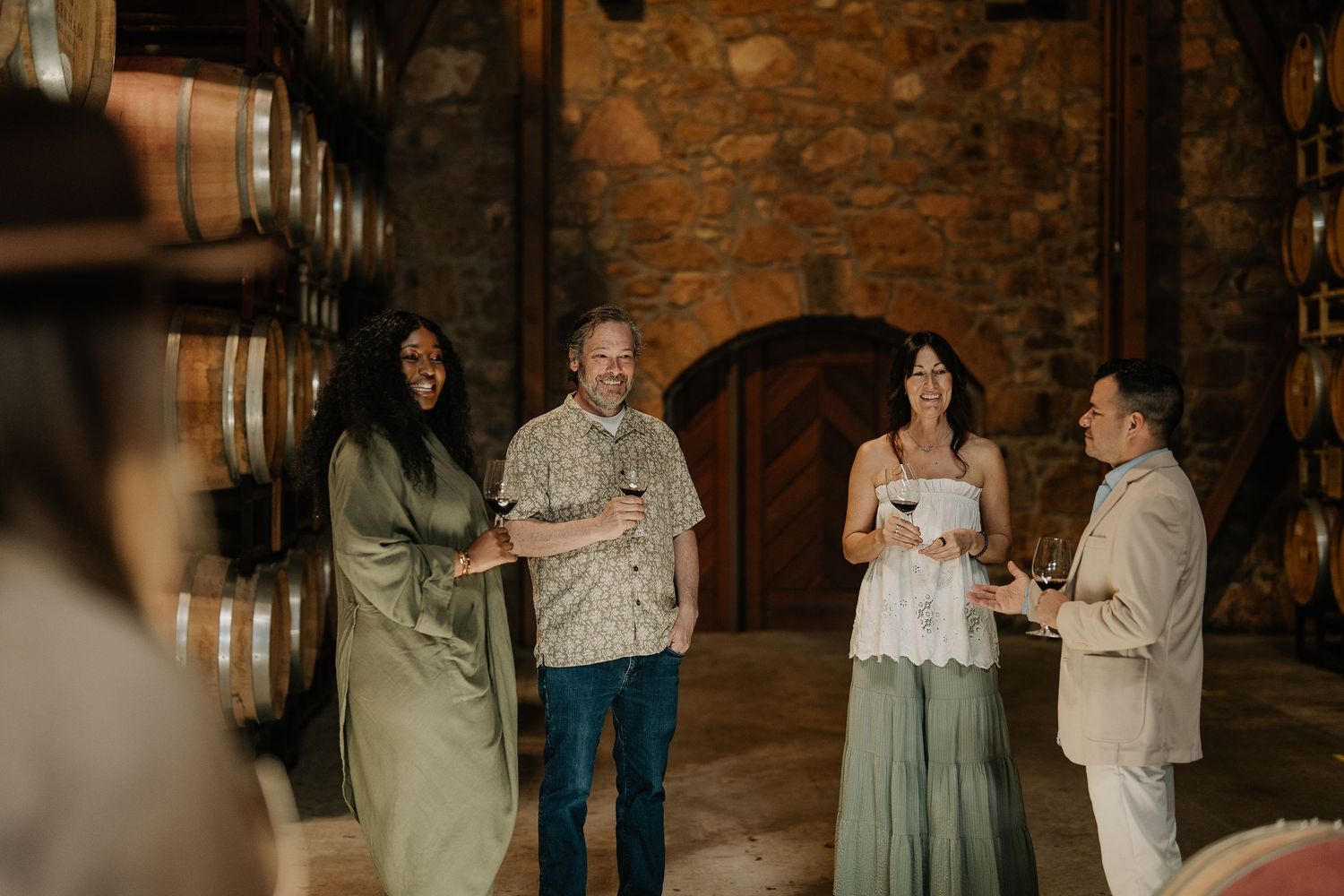Guests enjoy wine tasting in a rustic stone barrel cellar at a winery.