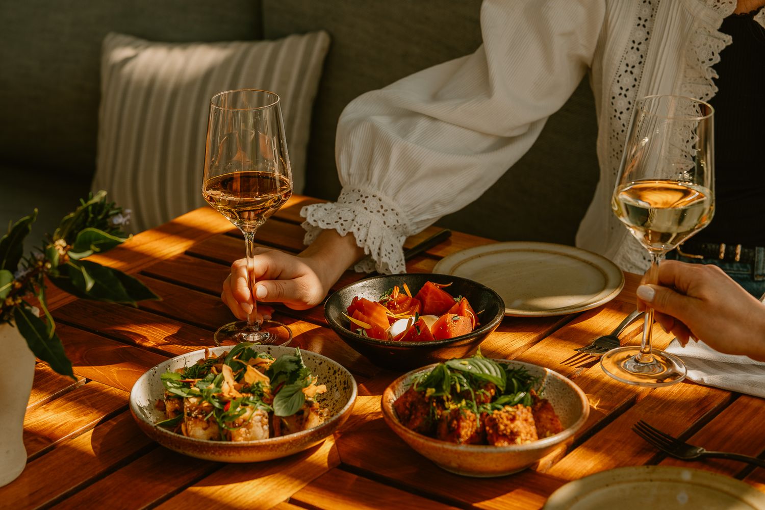 Candlelit dinner table set with elegant plates, wine glasses, and fresh salads in a romantic restaurant setting.