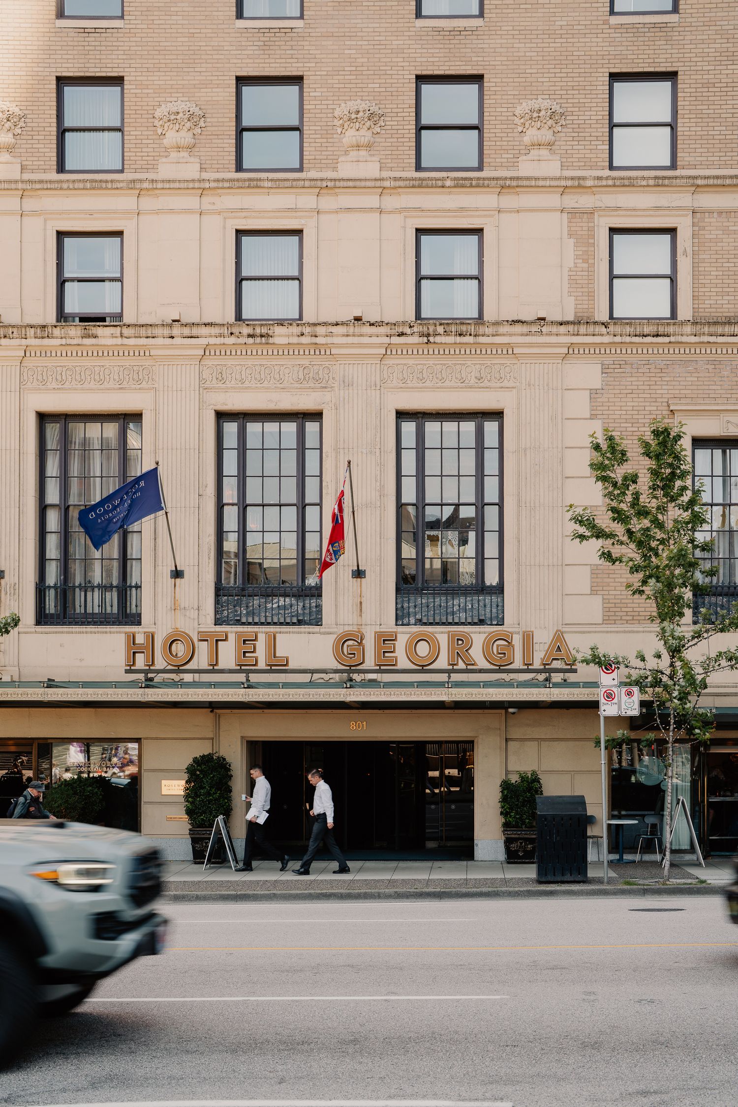 Historic Hotel Georgia building facade in downtown Vancouver with gold lettering and European flags at entrance.