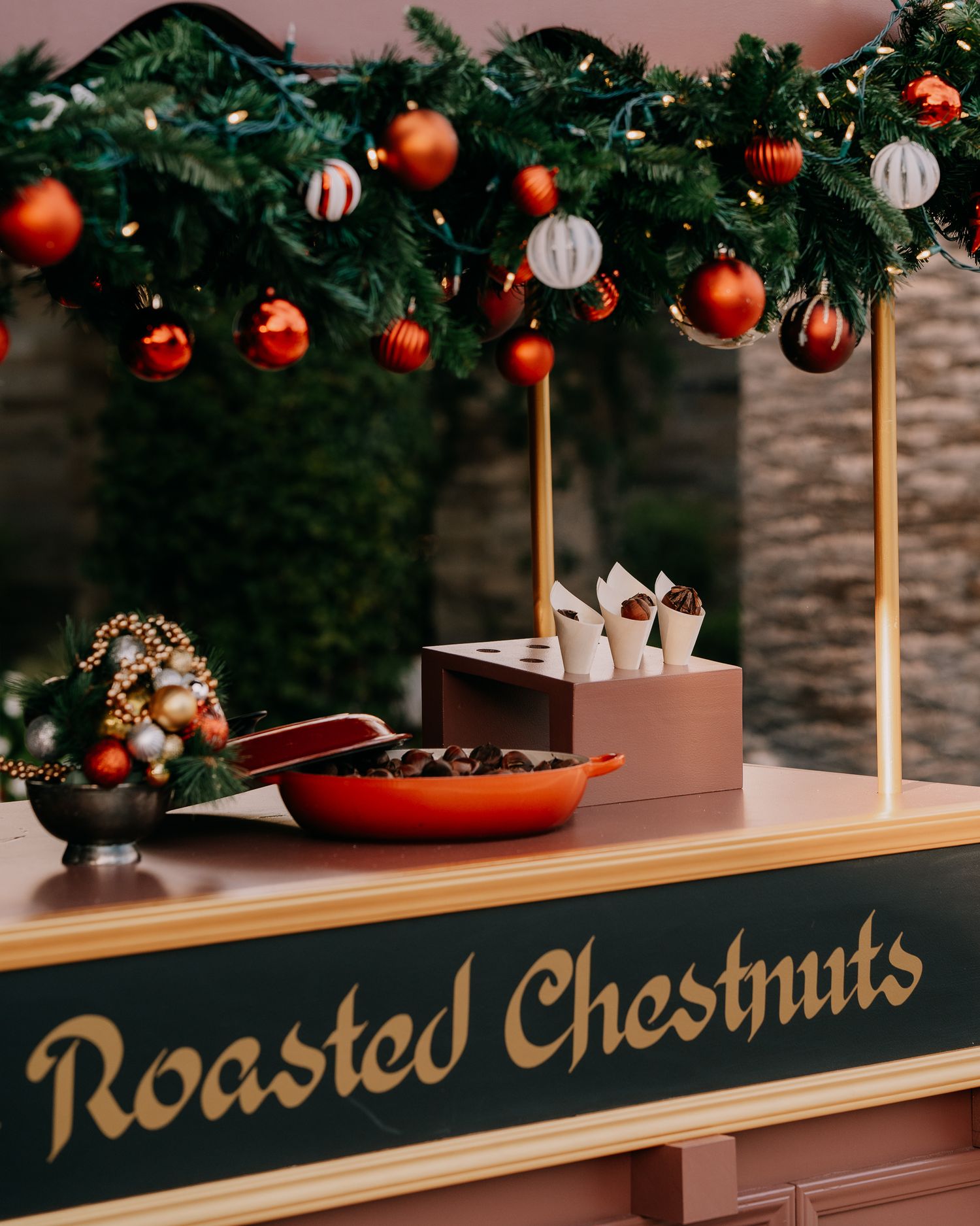 Christmas ornaments and decorative text adorn a wooden counter display at a festive holiday market.