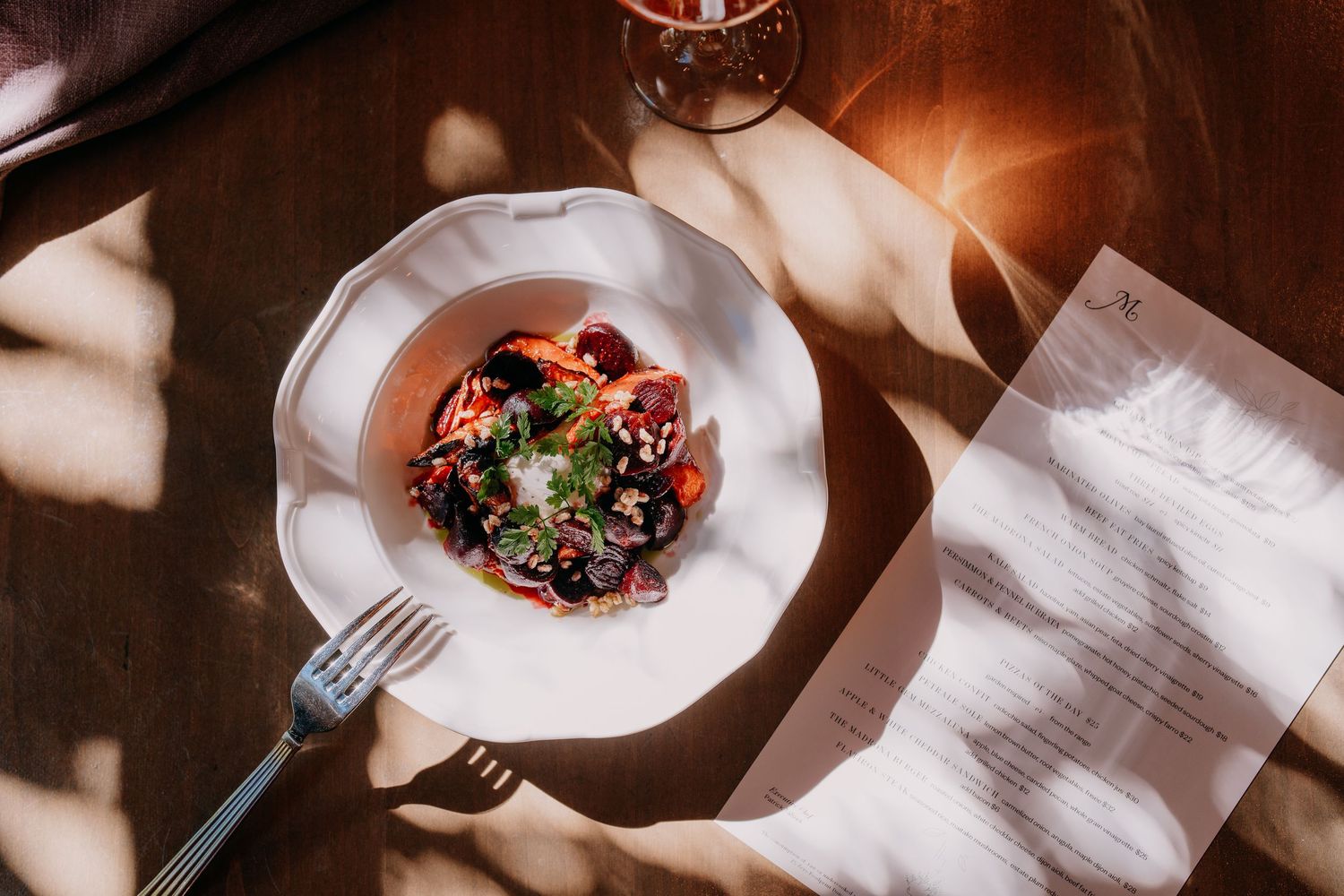 Elegantly plated dishes on white tablecloths with dramatic lighting and shadows.
