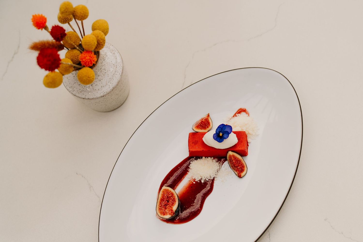 A series of white plates featuring colorful molecular gastronomy dishes with vibrant orange and red garnishes.