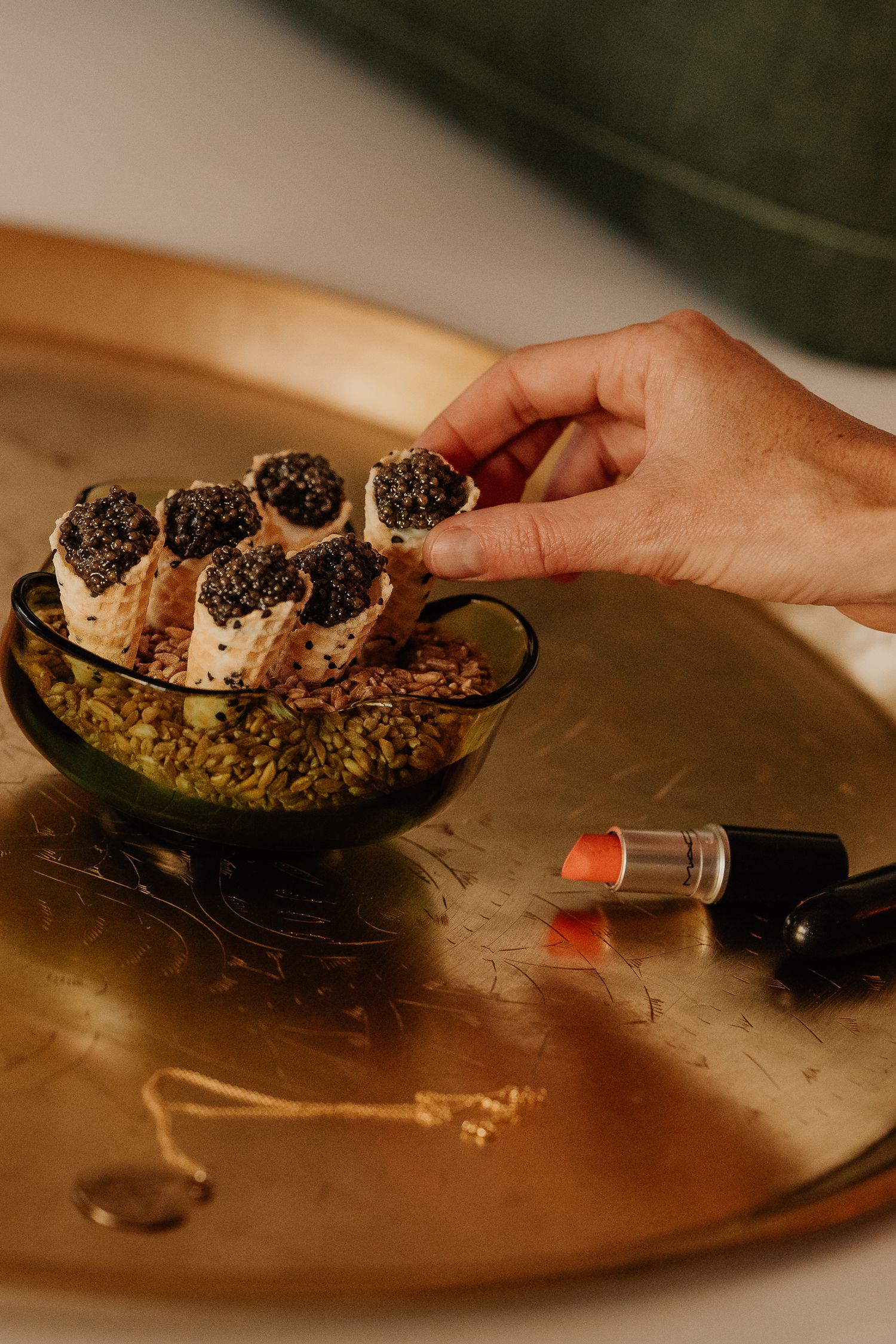 Black caviar served on crackers with garnish on a dark wooden serving platter in warm lighting.