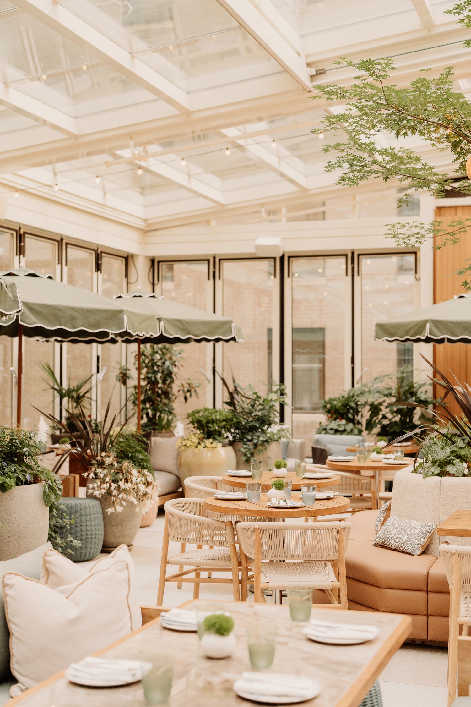 Modern restaurant interior with white decor, plush leather seating, and natural light streaming through skylights and windows.