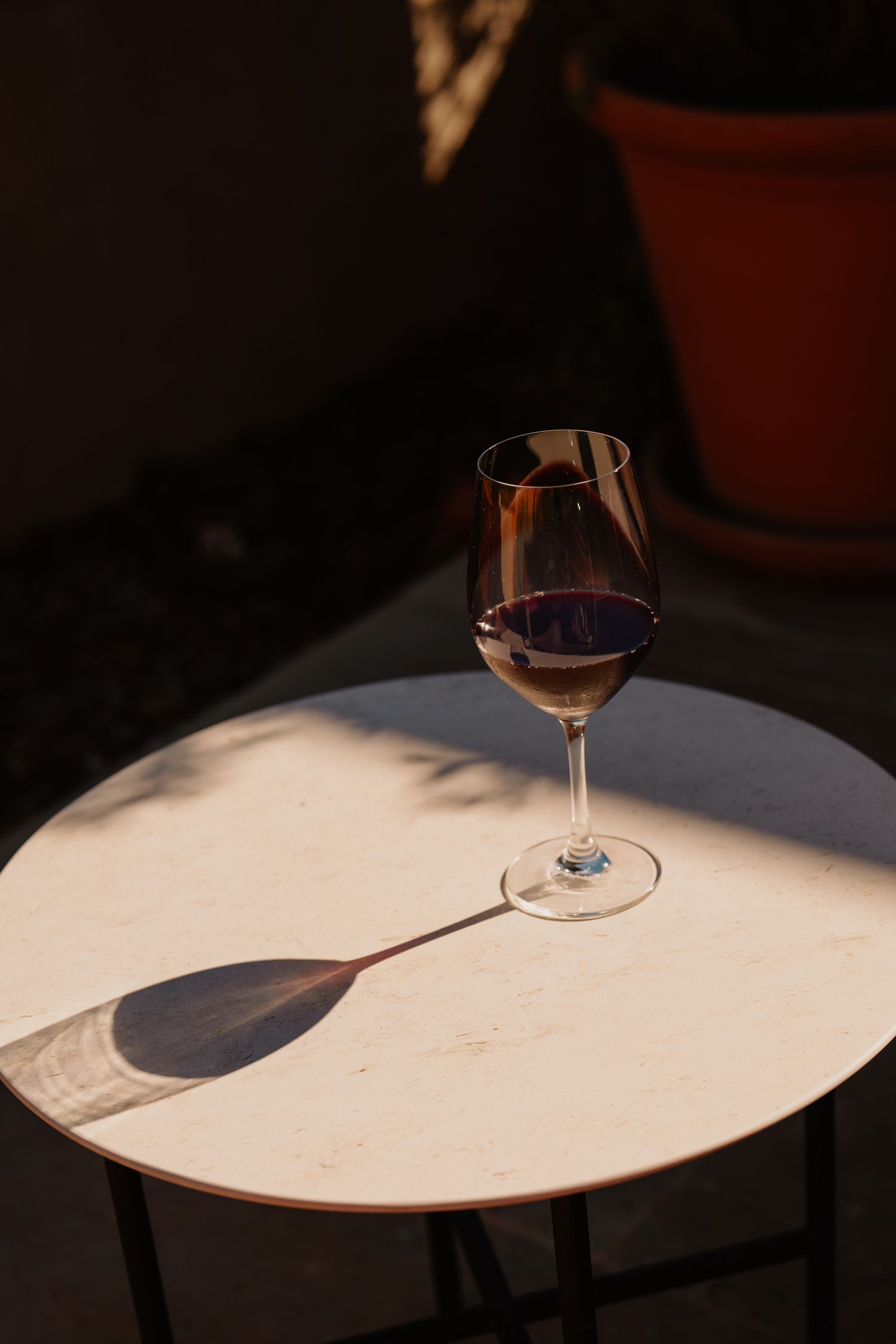 Wine glasses cast dramatic shadows on a white table surface in moody lighting creating an artistic composition.