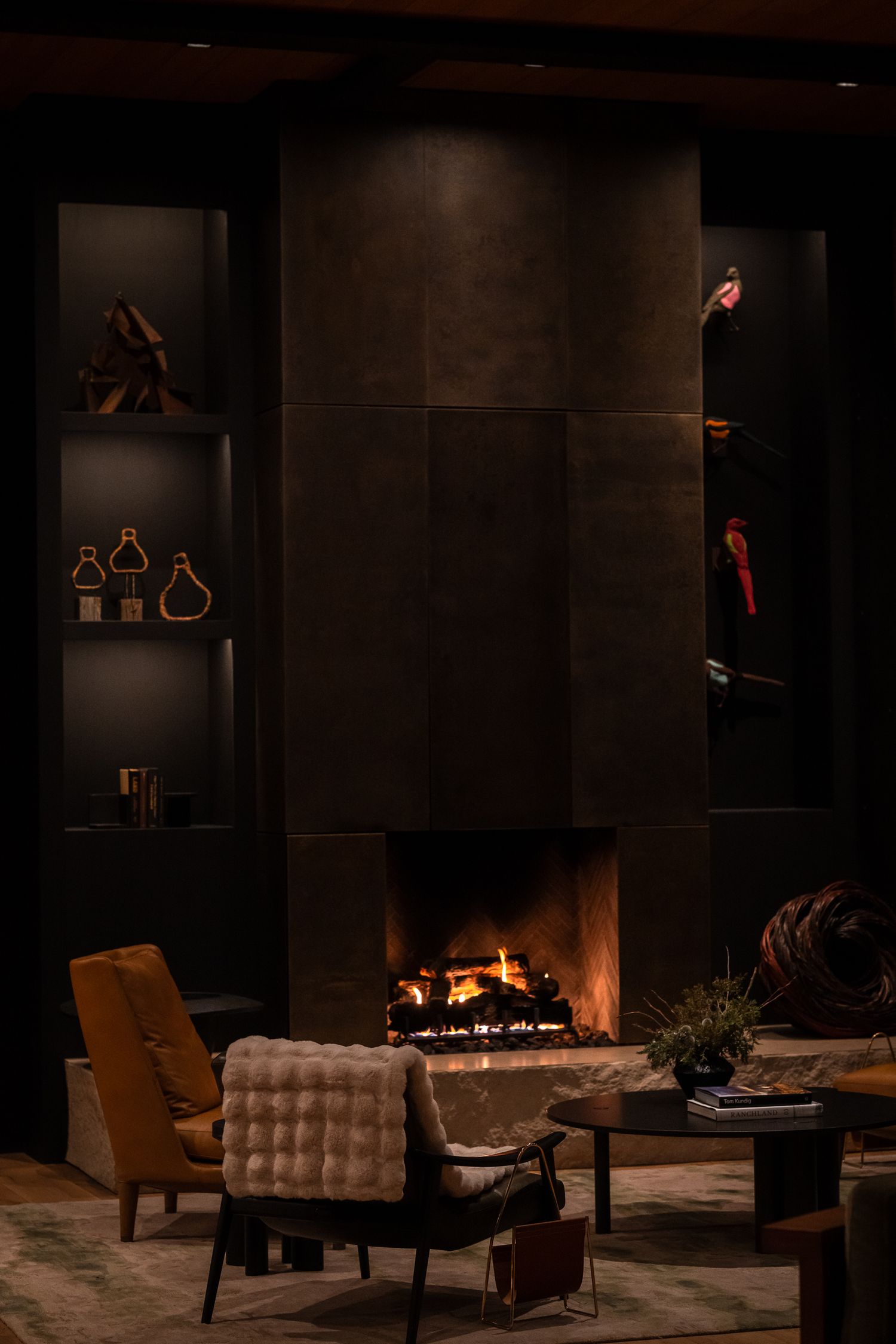 Cozy dark lounge area with modern armchairs and a sleek fireplace creating an intimate ambiance.