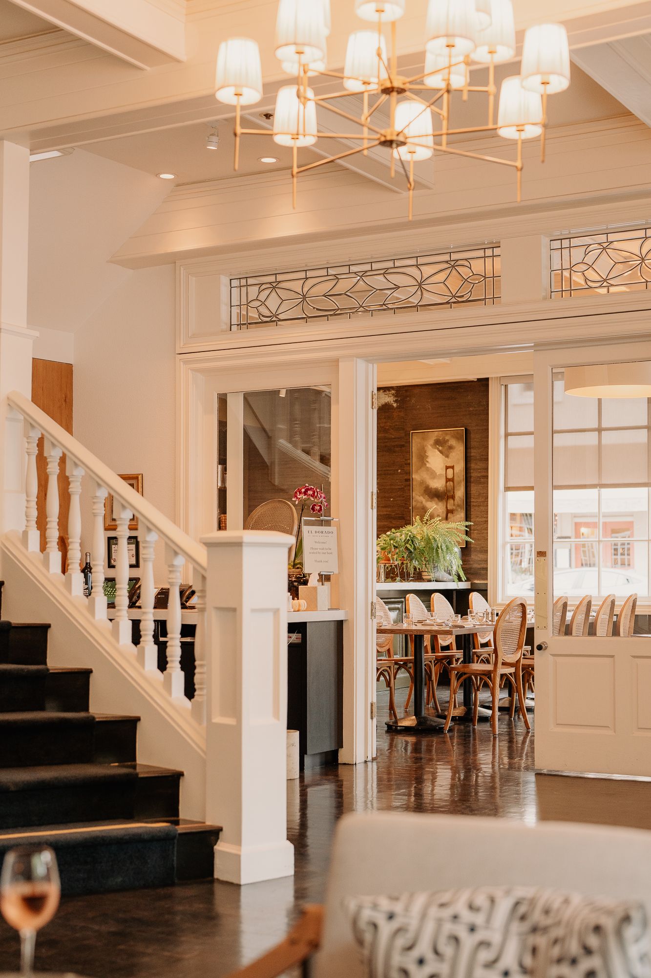 Elegant white event venue interior with coffered ceiling, chandeliers and hardwood floors in a bright open space.