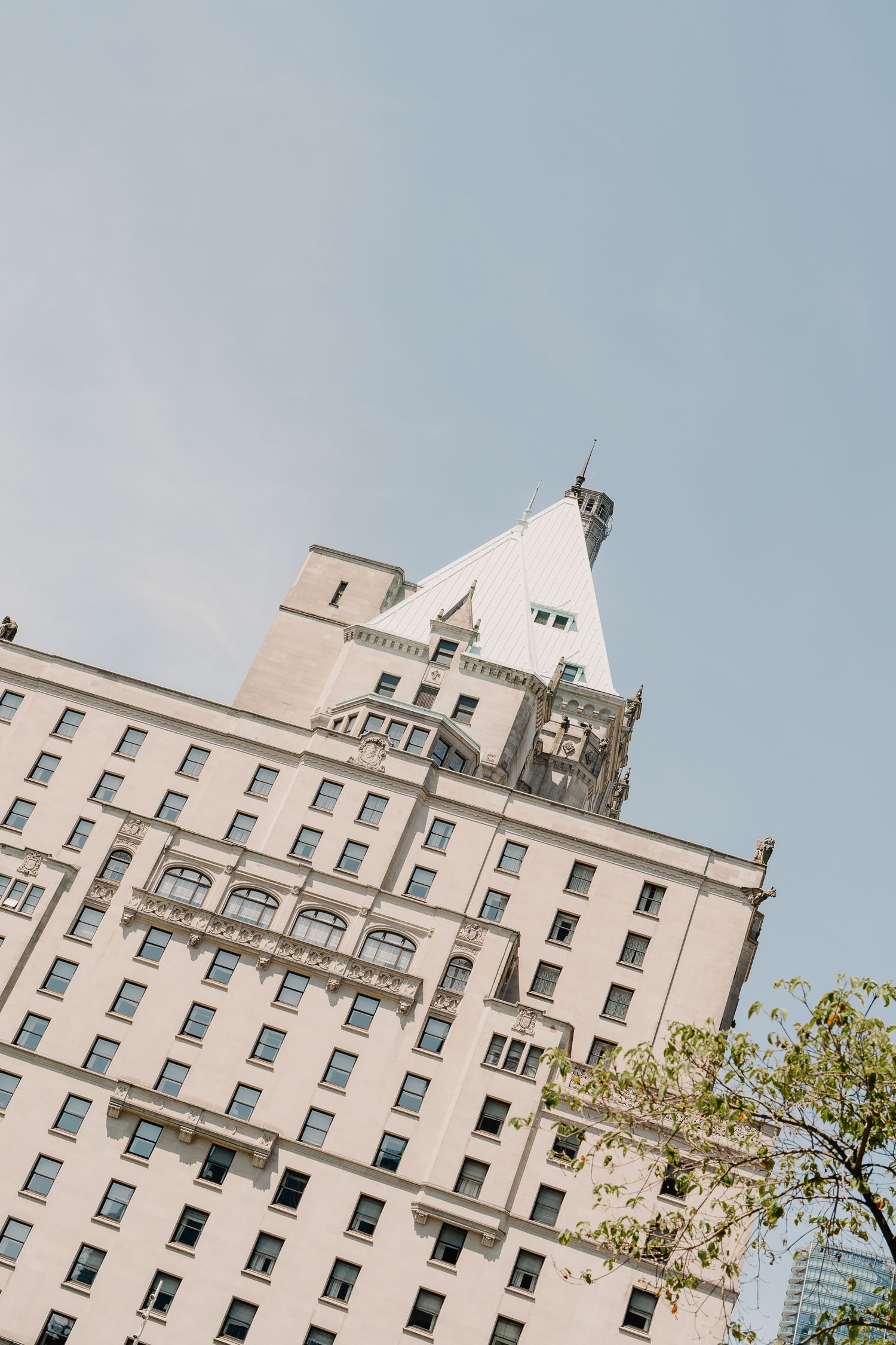 A tall white historic apartment building with ornate architecture and a decorative tower rises against a pale blue sky.