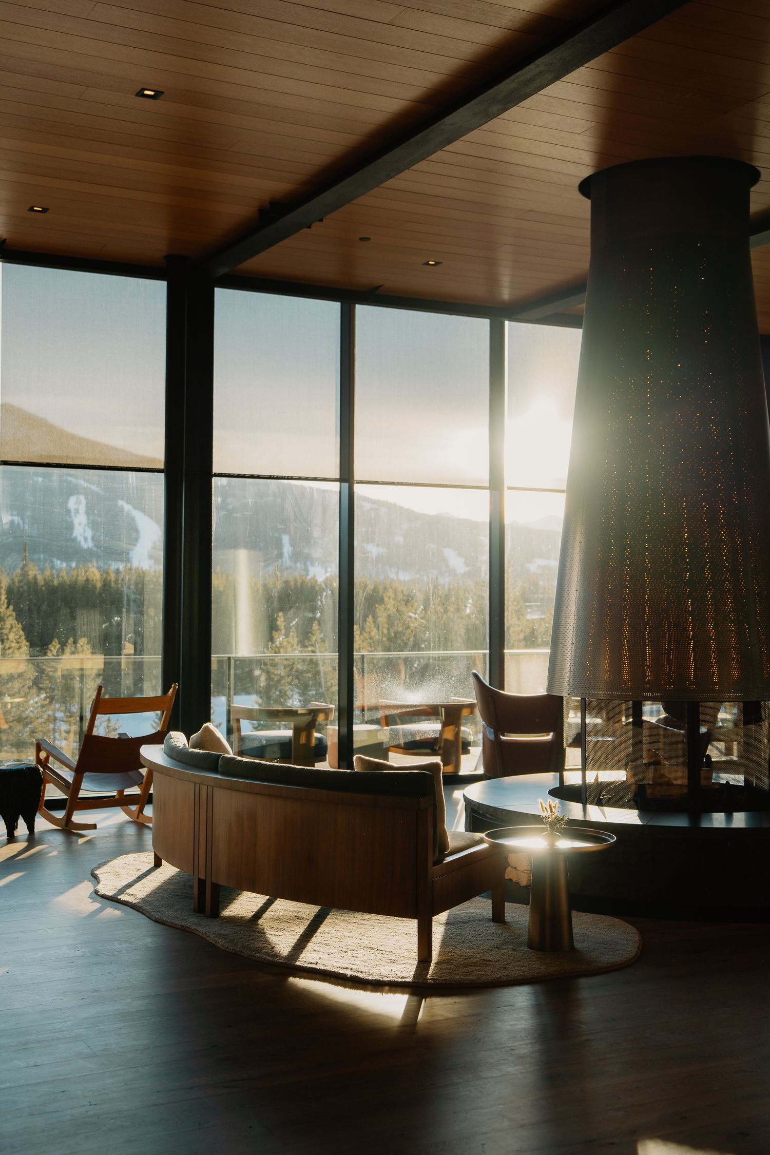 Modern mountain lodge lounge with panoramic windows showcasing snowy forest views and comfortable seating areas.