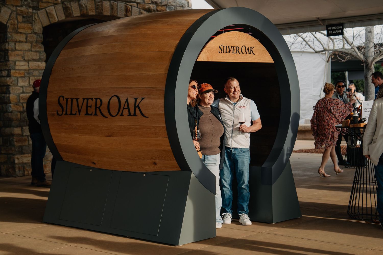 Couple posing inside a large decorative Silver Oak wine barrel display at a wine event.