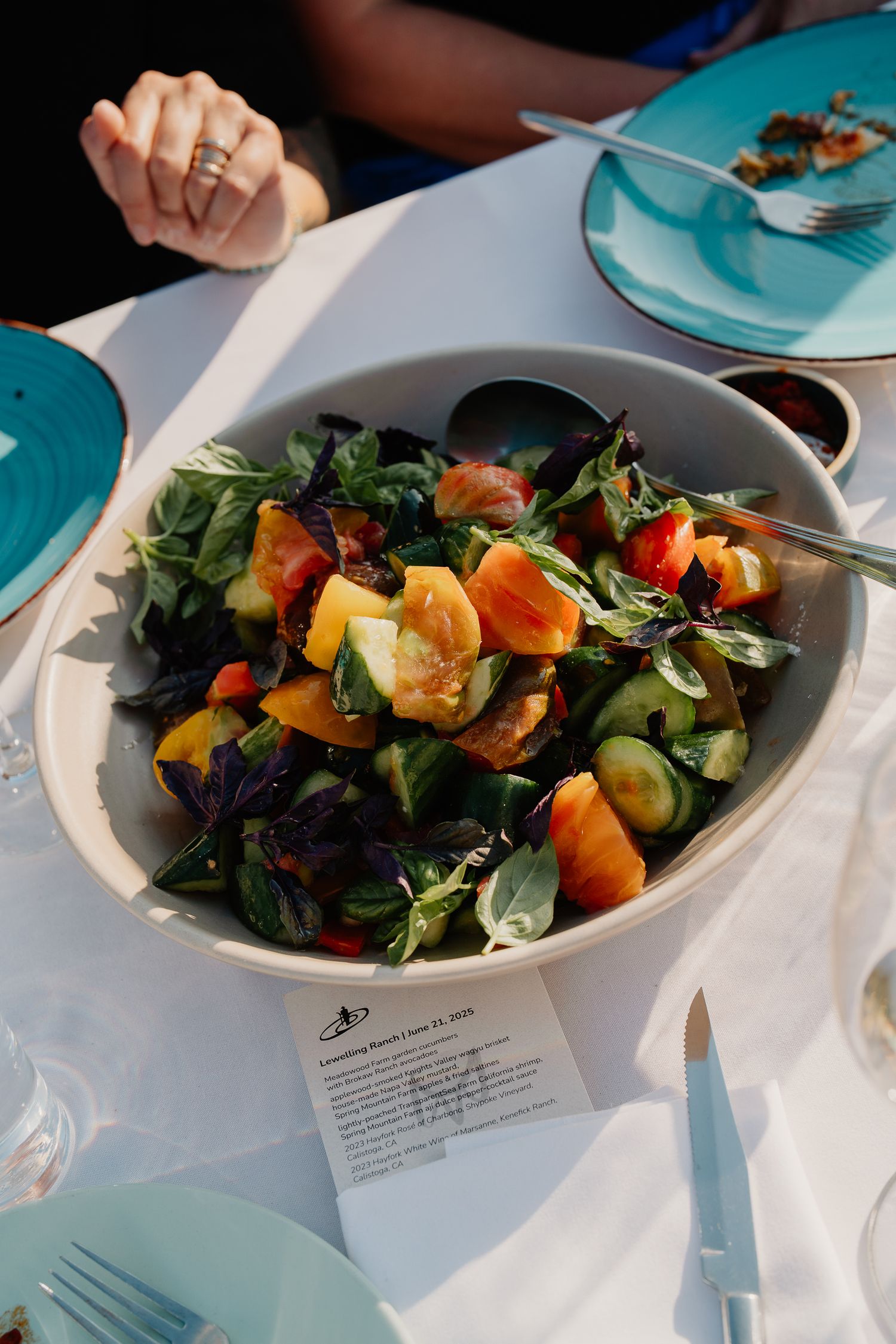 Fresh garden salad with colorful ingredients served on turquoise plates at an outdoor dining event.