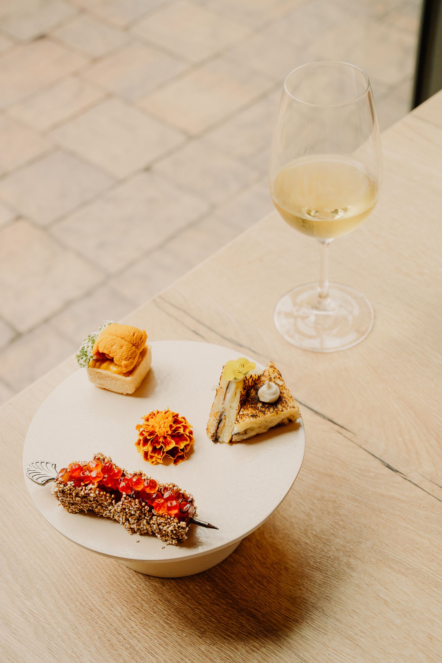 Elegant plated appetizers with colorful garnishes served on white plates against a light textured surface.
