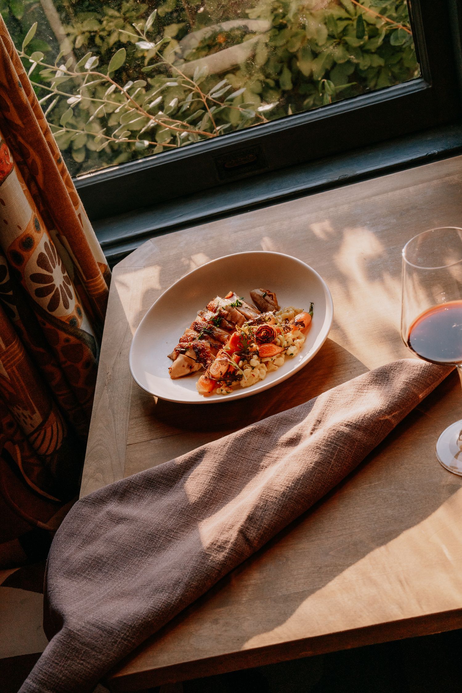 White plate with food served near window with natural light streaming in and greenery visible outside.