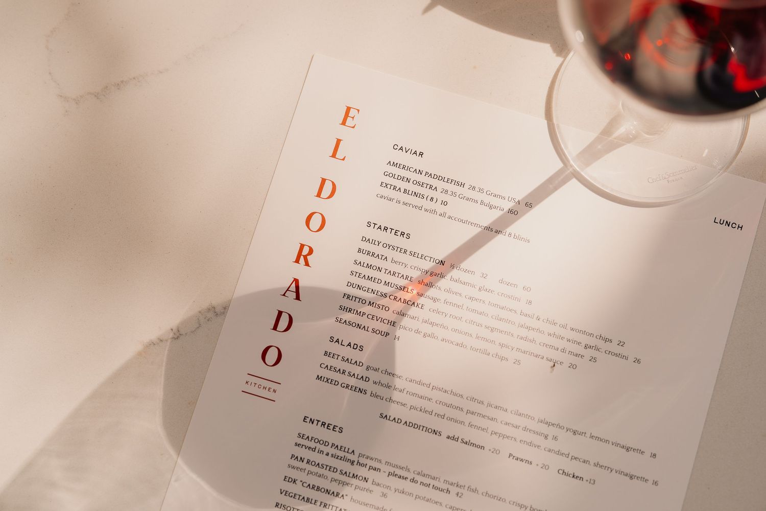 Eldorado restaurant menu on marble table with a glass of red wine, elegant dining experience.