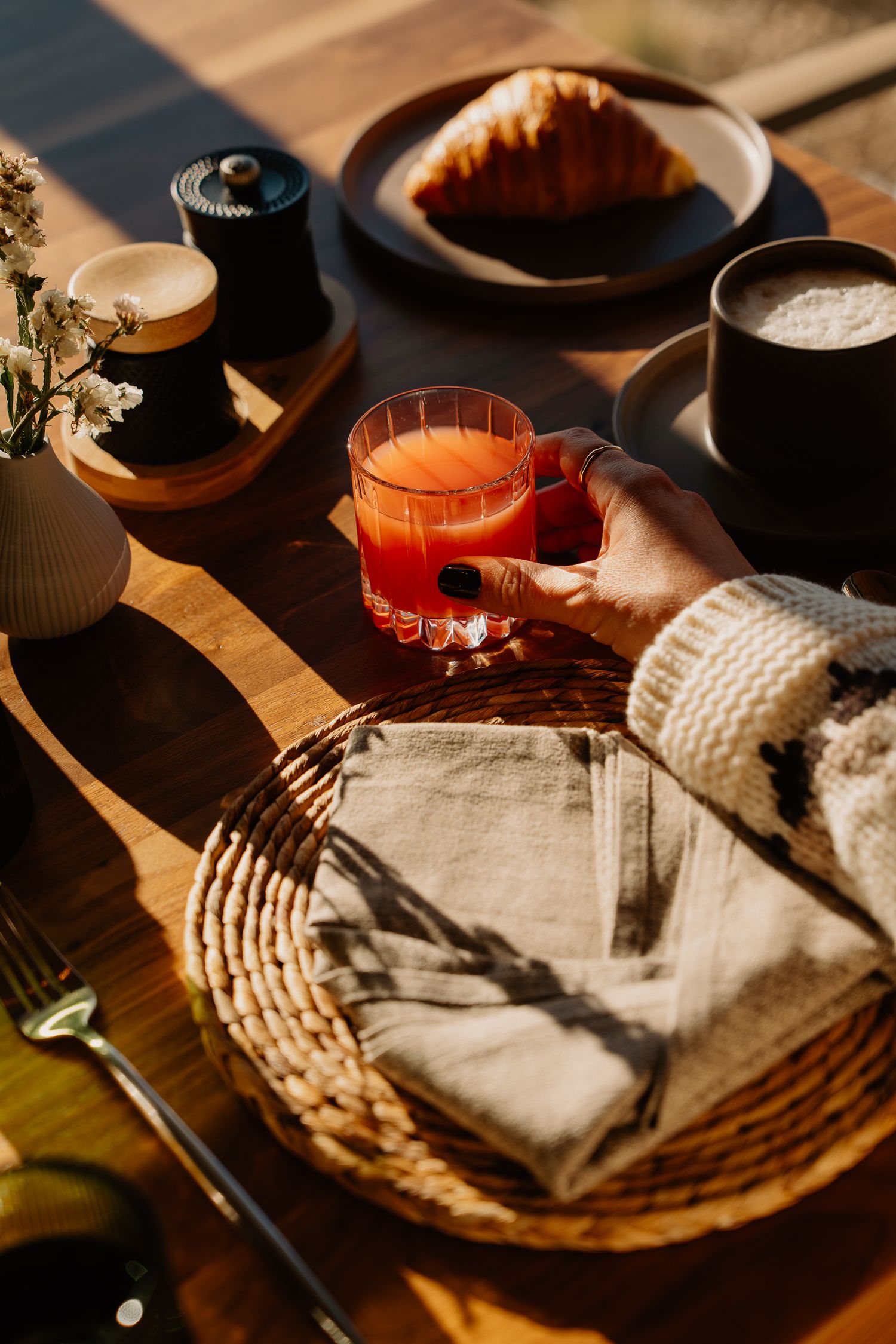Rustic place settings with woven placemats and napkins on a wooden table in warm lighting.