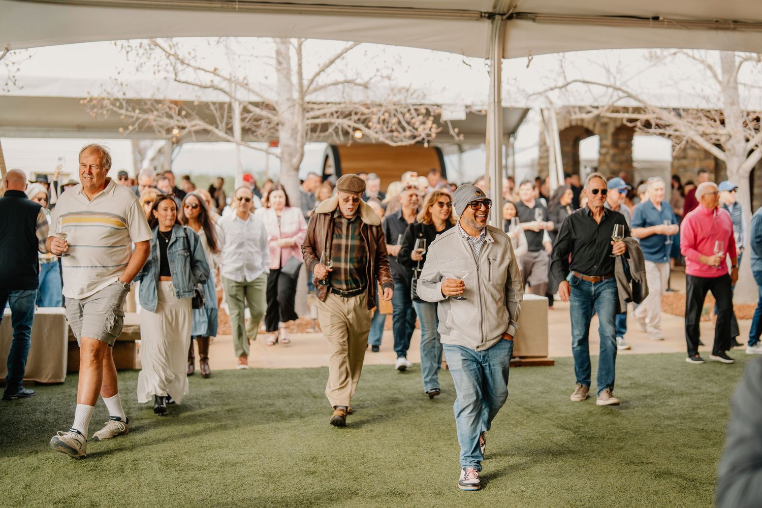Crowd of people walking under a tent at an outdoor festival event.