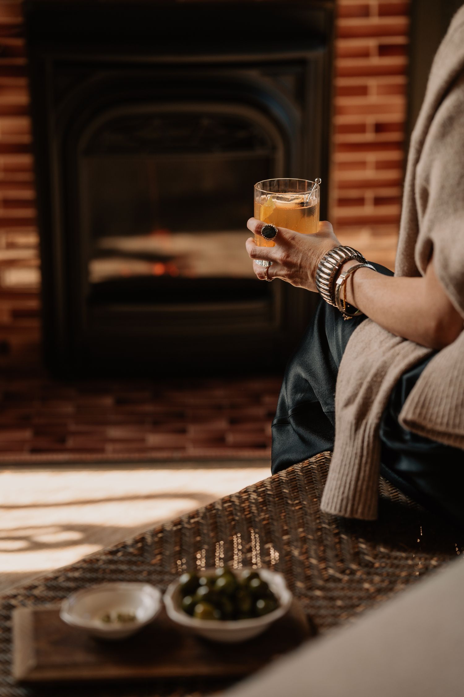Warm sunlit dining scene with drinks and place settings on a textured table runner.
