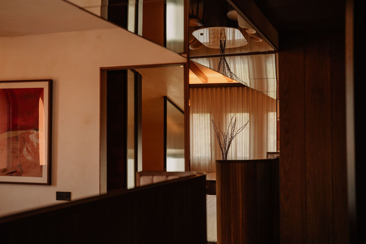 Modern hallway with wooden floors and glass walls showcases contemporary interior design with natural lighting.