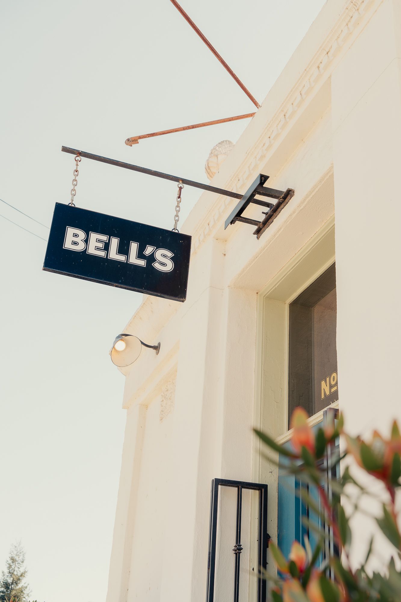 Bell's restaurant exterior sign hanging on a white building facade with warm lighting and decorative ironwork.