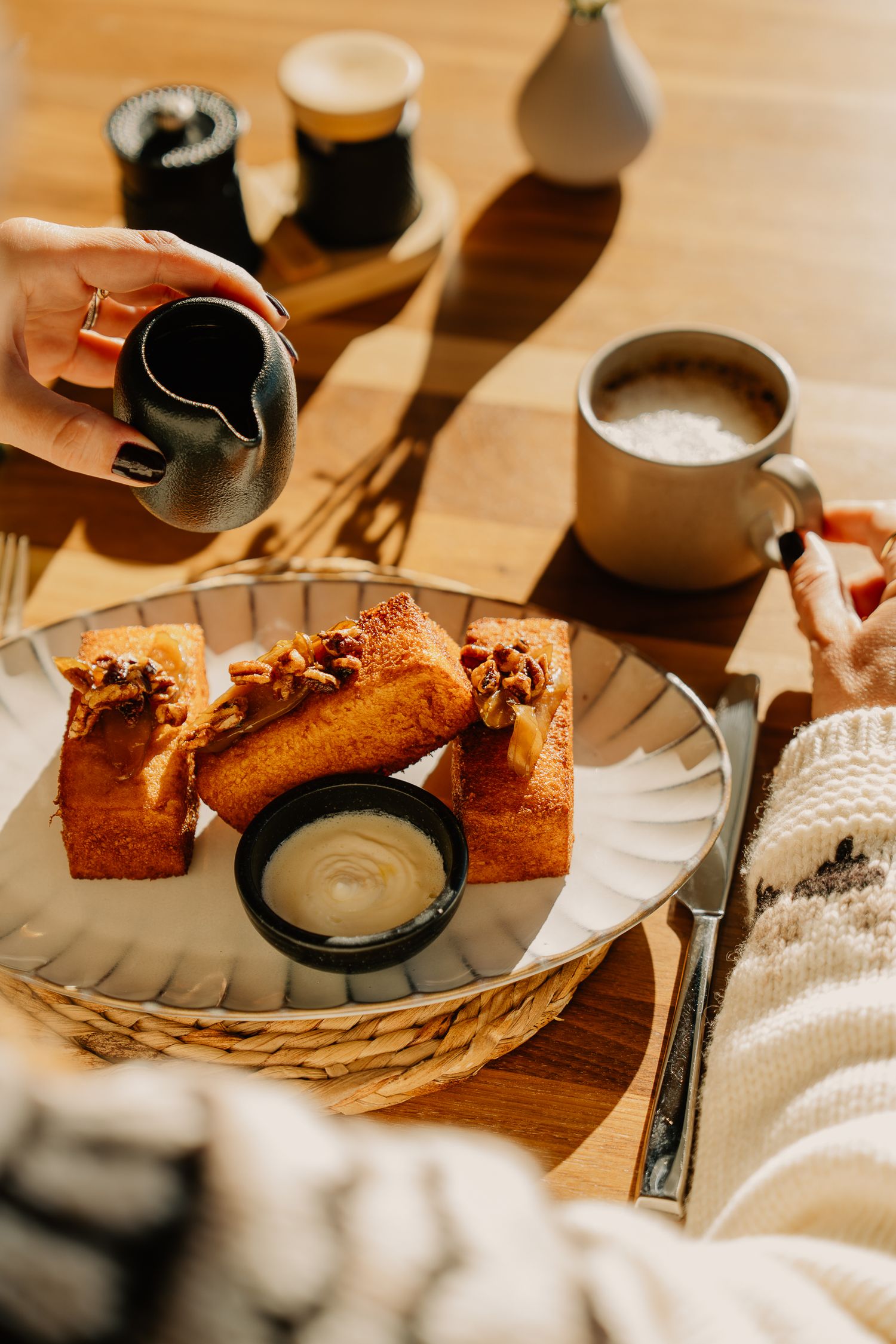 Cozy breakfast scene with french toast and coffee on a wooden table with warm lighting and shadows.