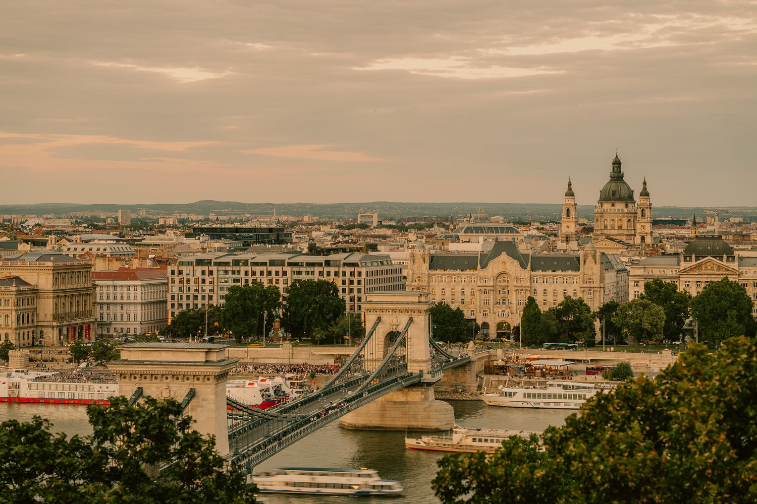Aerial view of Budapest cityscape with the Chain Bridge spanning the Danube River at golden hour dusk.