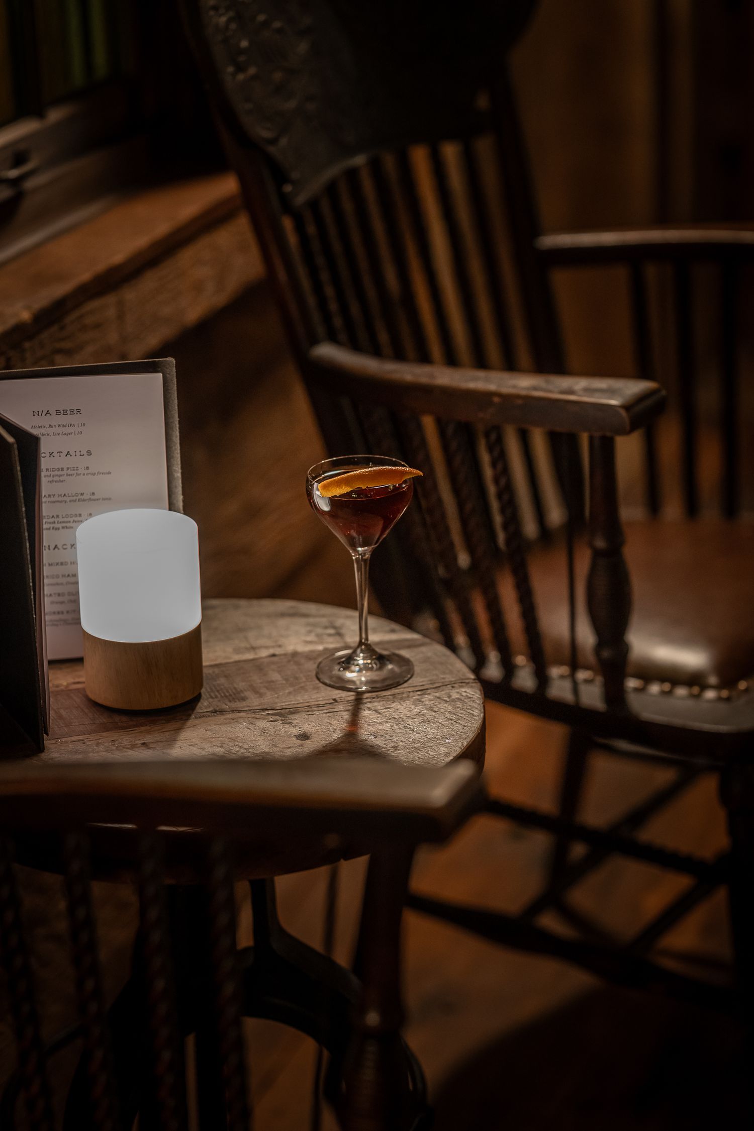 Cozy dimly lit bar setting with cocktail glasses and wooden furniture.