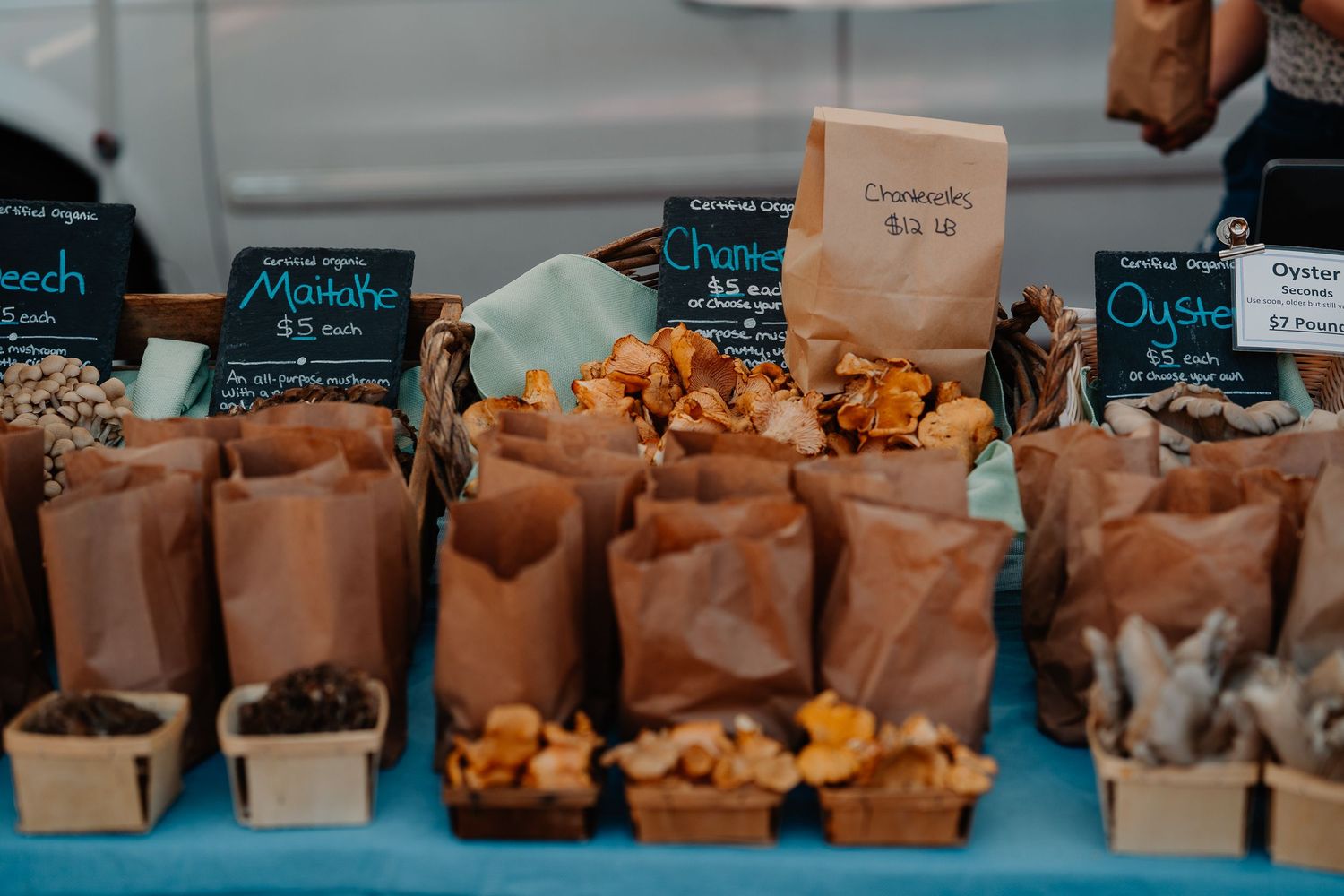 Brown paper bags filled with assorted nuts and snacks displayed on a blue surface at a market.