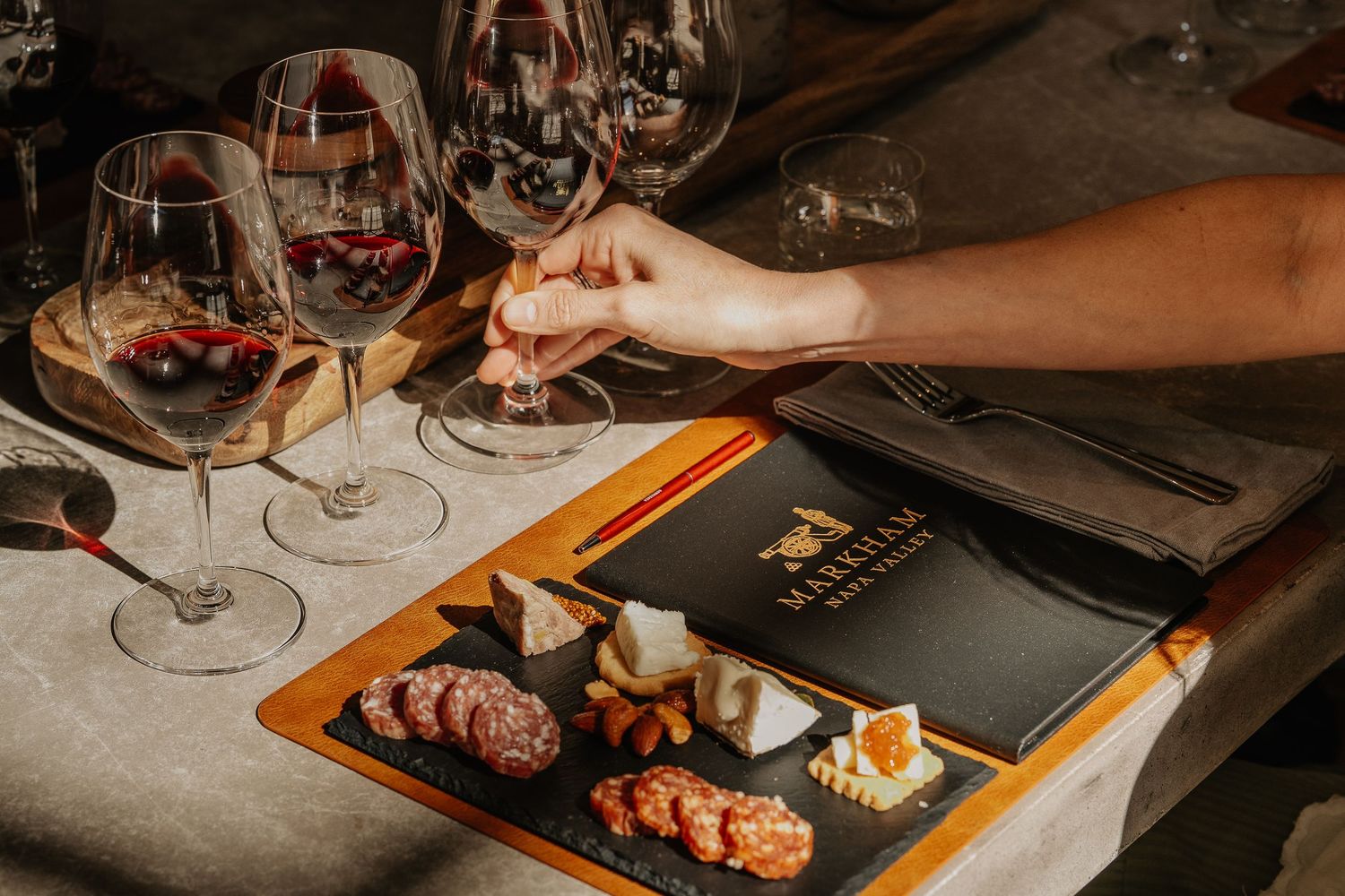 Elegant wine tasting with red wines and gourmet charcuterie cheese board on a slate platter.