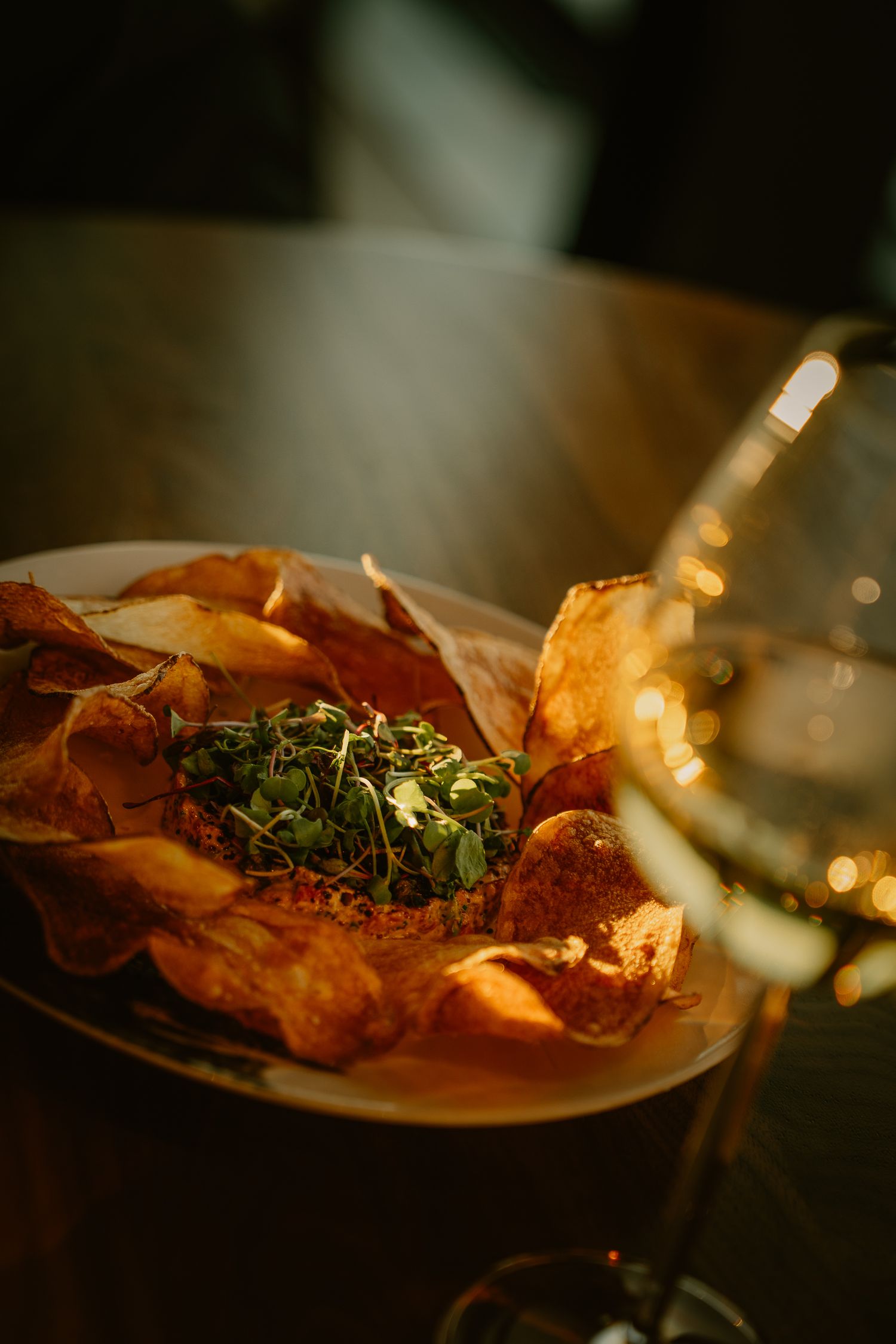Close-up sequence of a gourmet dish with prosciutto and fresh herbs on a white plate in dim lighting.