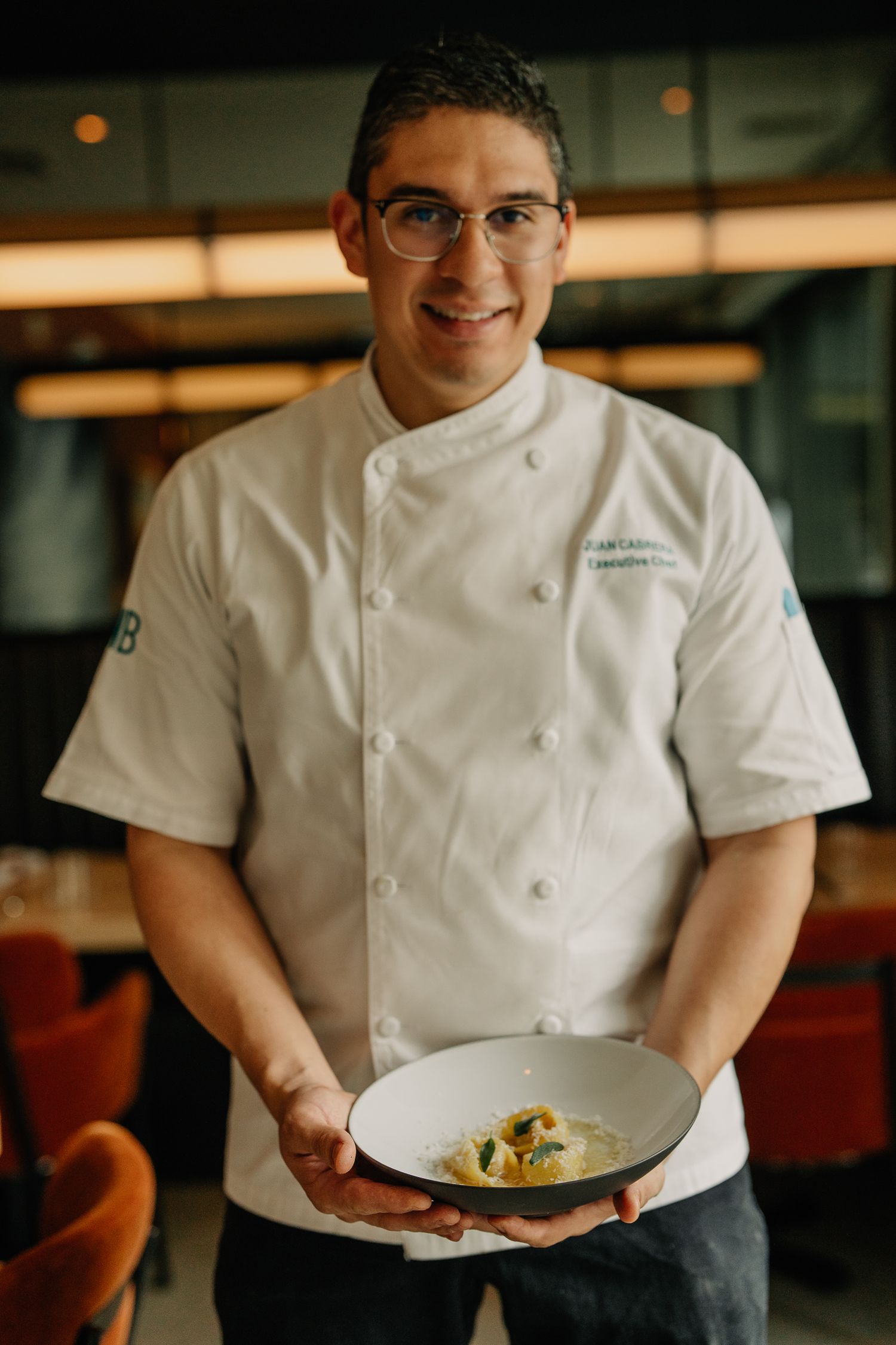 Professional kitchen staff in white chef coats serving plated dishes in restaurant setting.